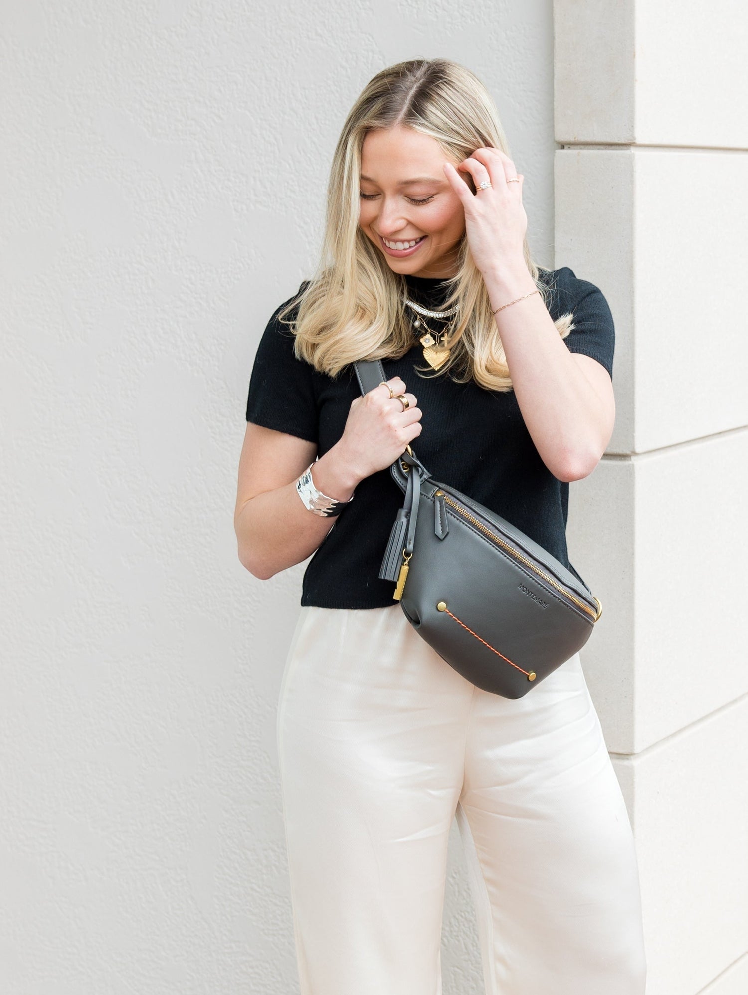 Woman holding a black handbag against a light-colored wall