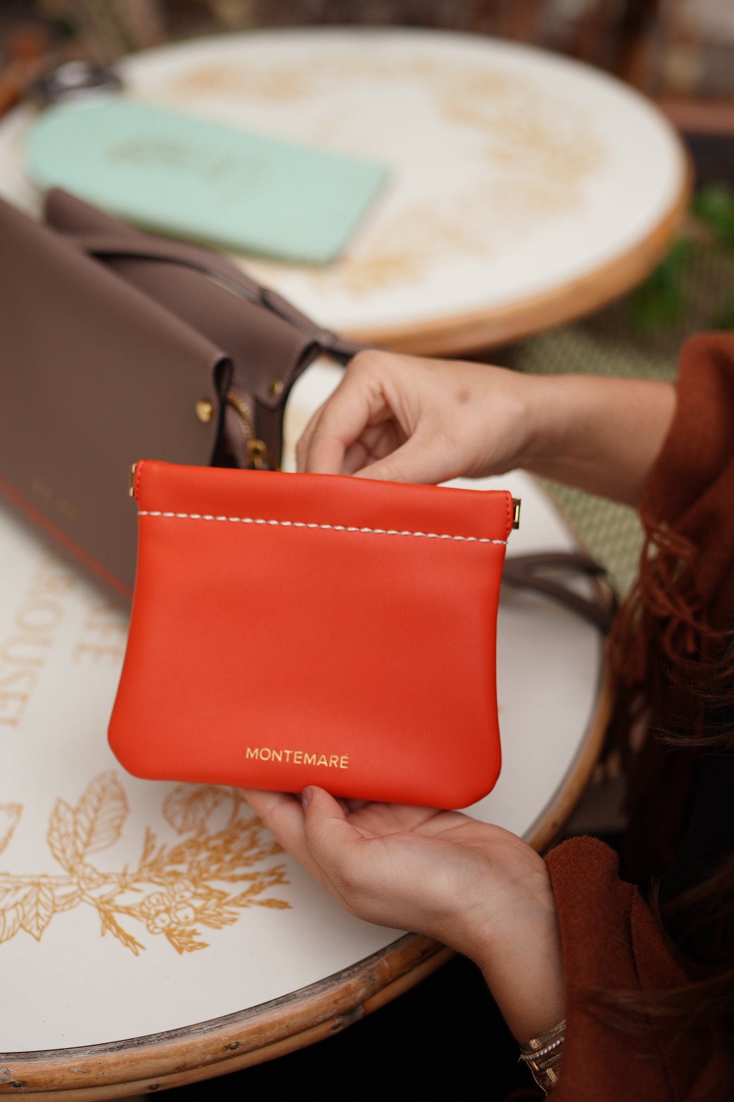 Person holding a red Montemare square pouch with a blurred background