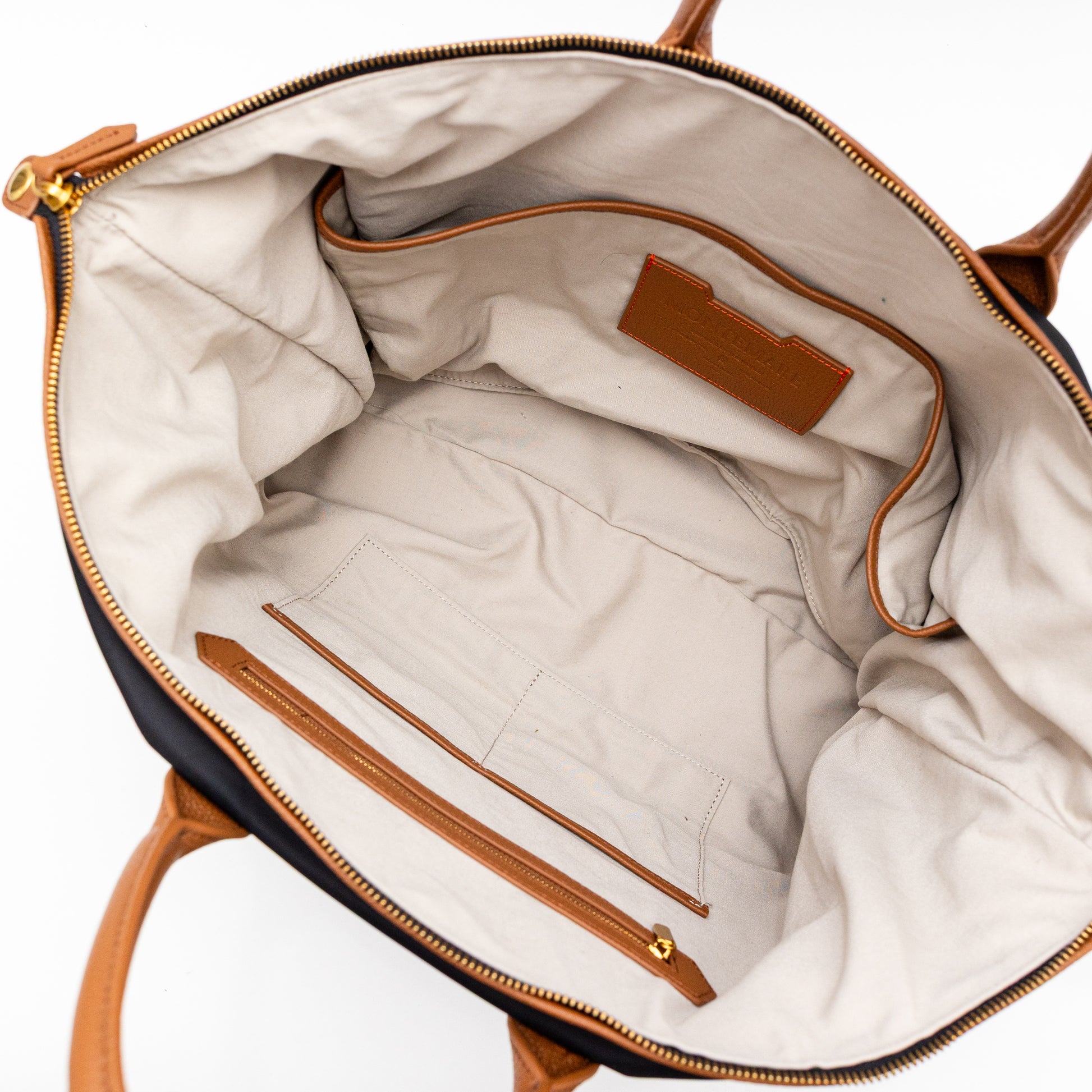 Interior of a black carry on bag with brown leather accents on a white background