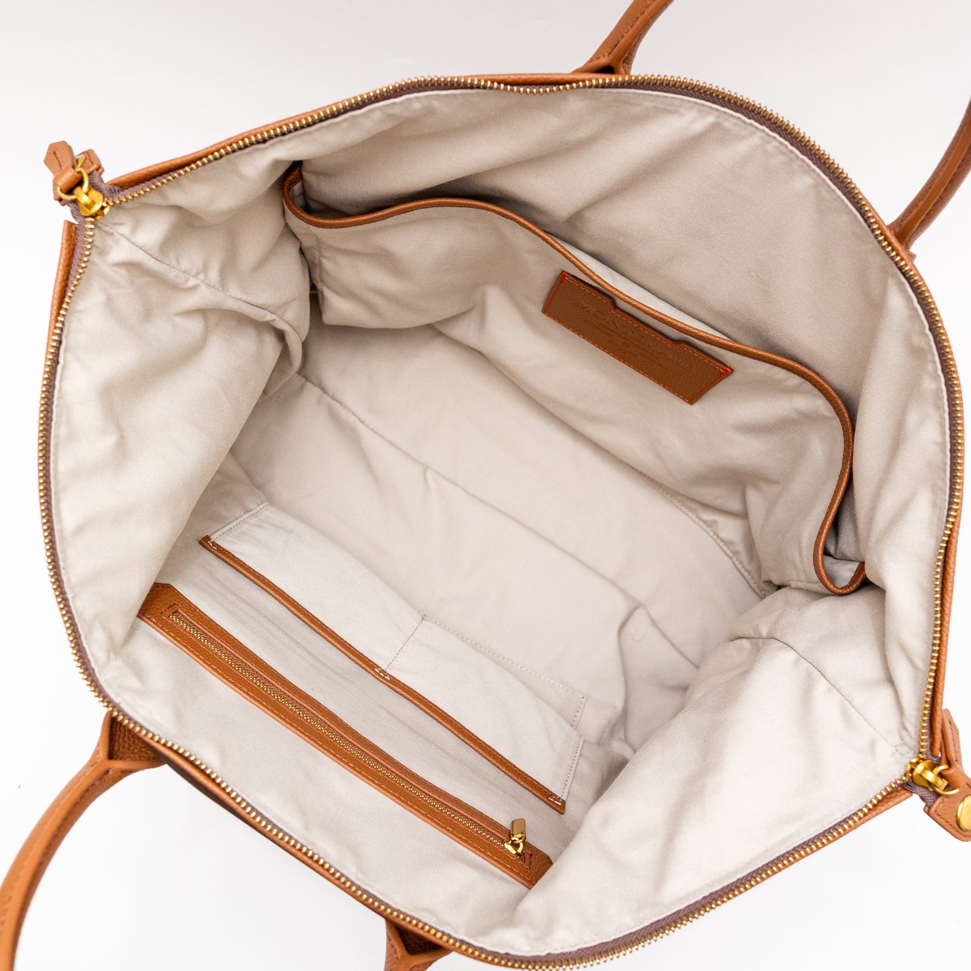 Interior of brown carry on bag with brown leather trim on a white background