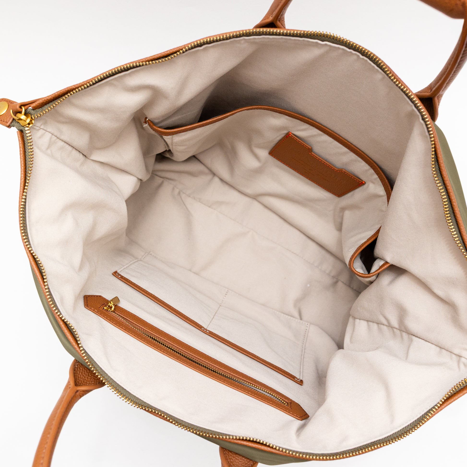 Interior of a green carry on bag with brown leather trim on a white background