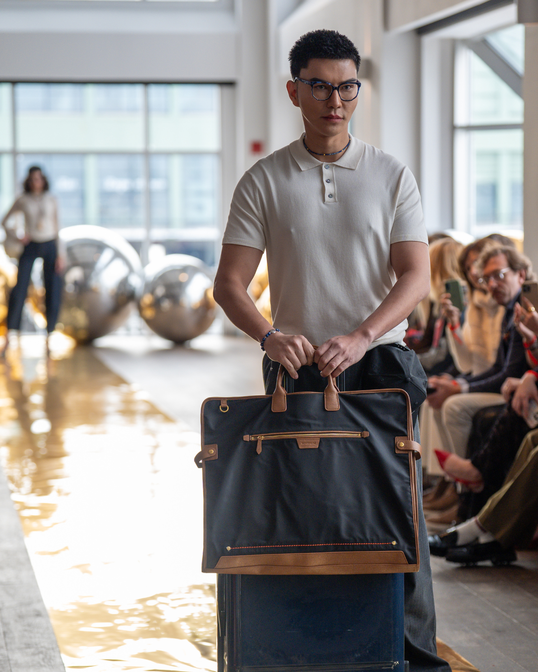 Black garment bag carried by male model on fashion runway
