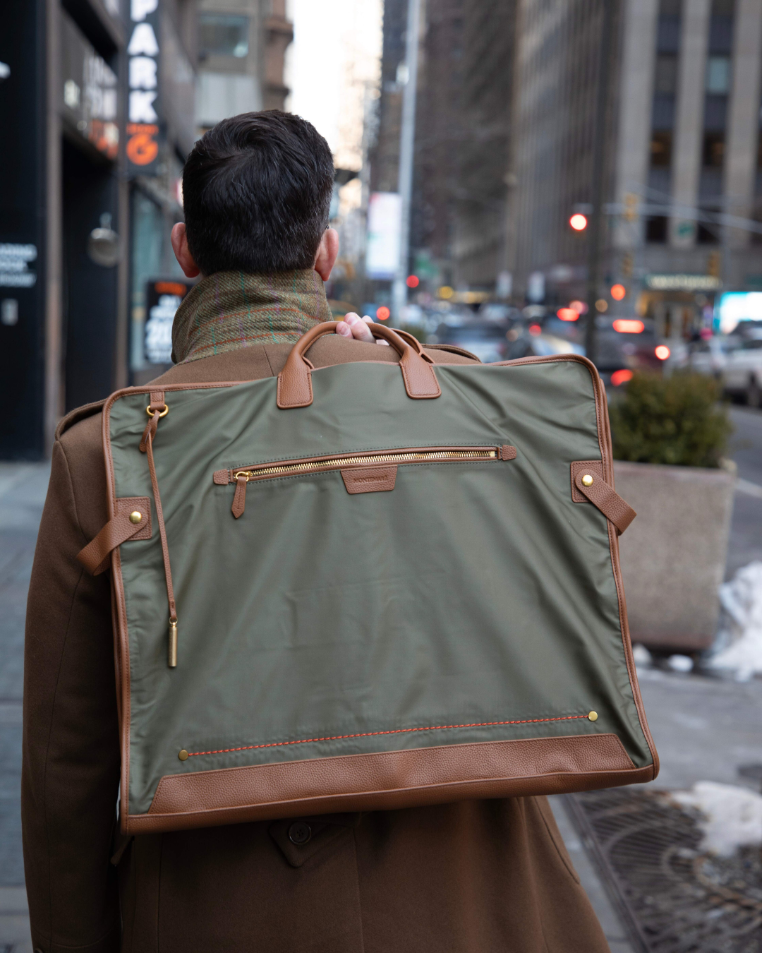 Olive garment bag carried by man walking in city