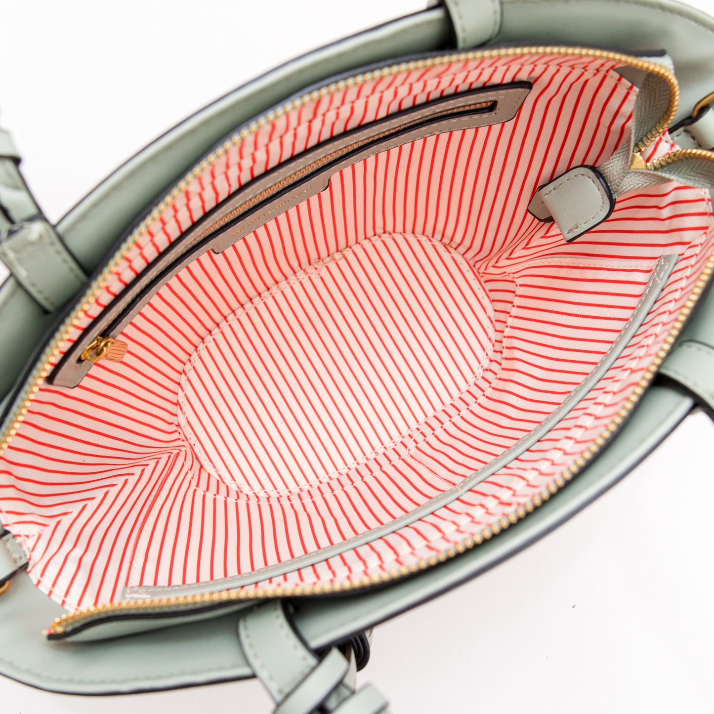 Open blue handbag with pink striped interior on a white background