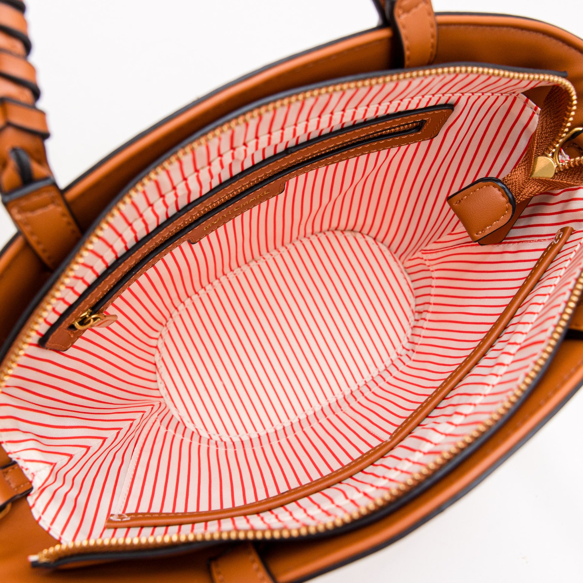 Cognac leather handbag with a red and white striped lining on a white background