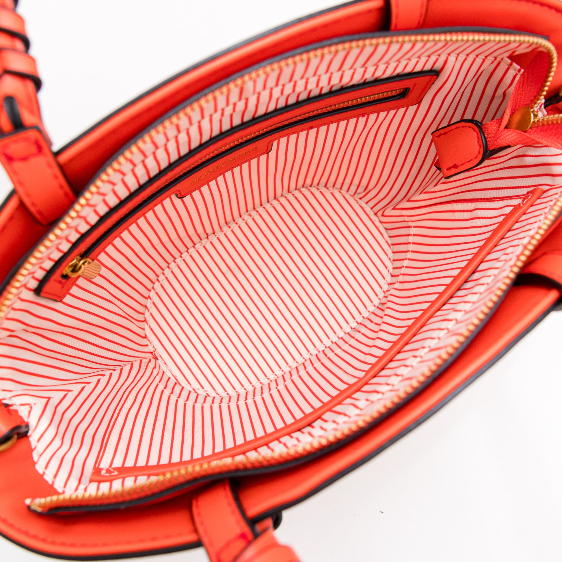 Close-up of a orange handbag with a striped lining on a white background