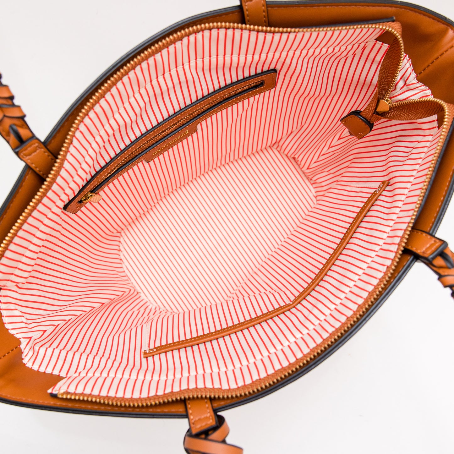 Open brown handbag with red and white striped lining on a white background