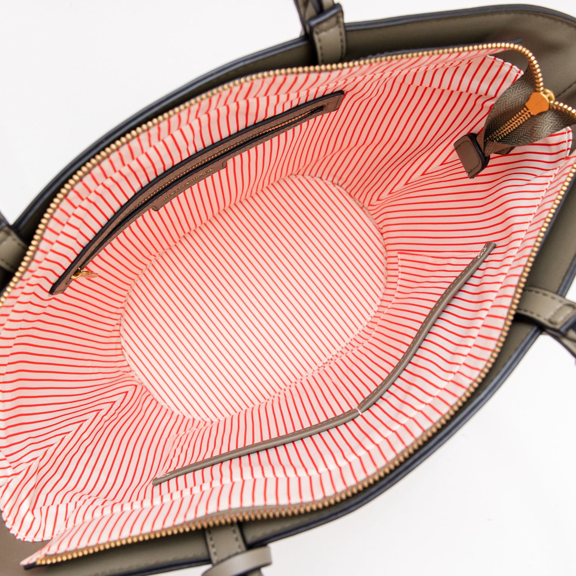 Open handbag revealing a pink interior with red stripes on a white background