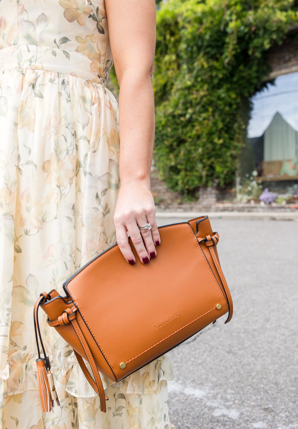 Person holding a brown leather handbag outdoors