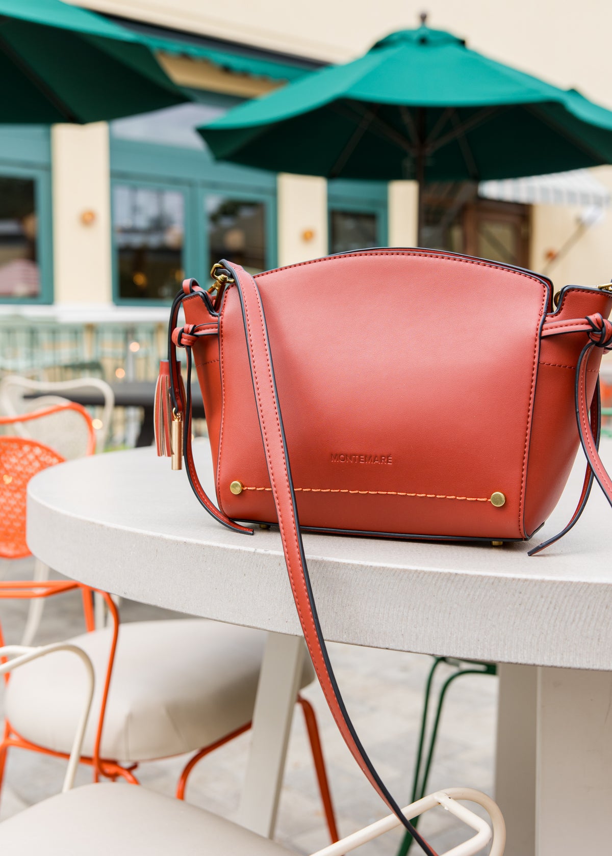 Red handbag on a table with outdoor cafe setting