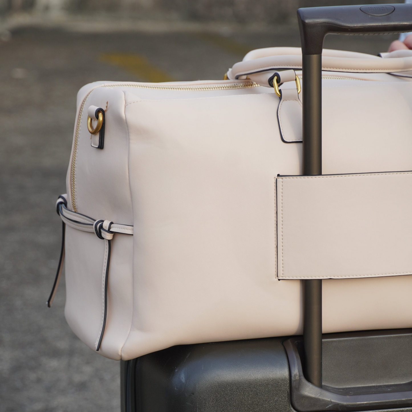 Montemare Roma Duffel in ivory colorway attached on a black luggage