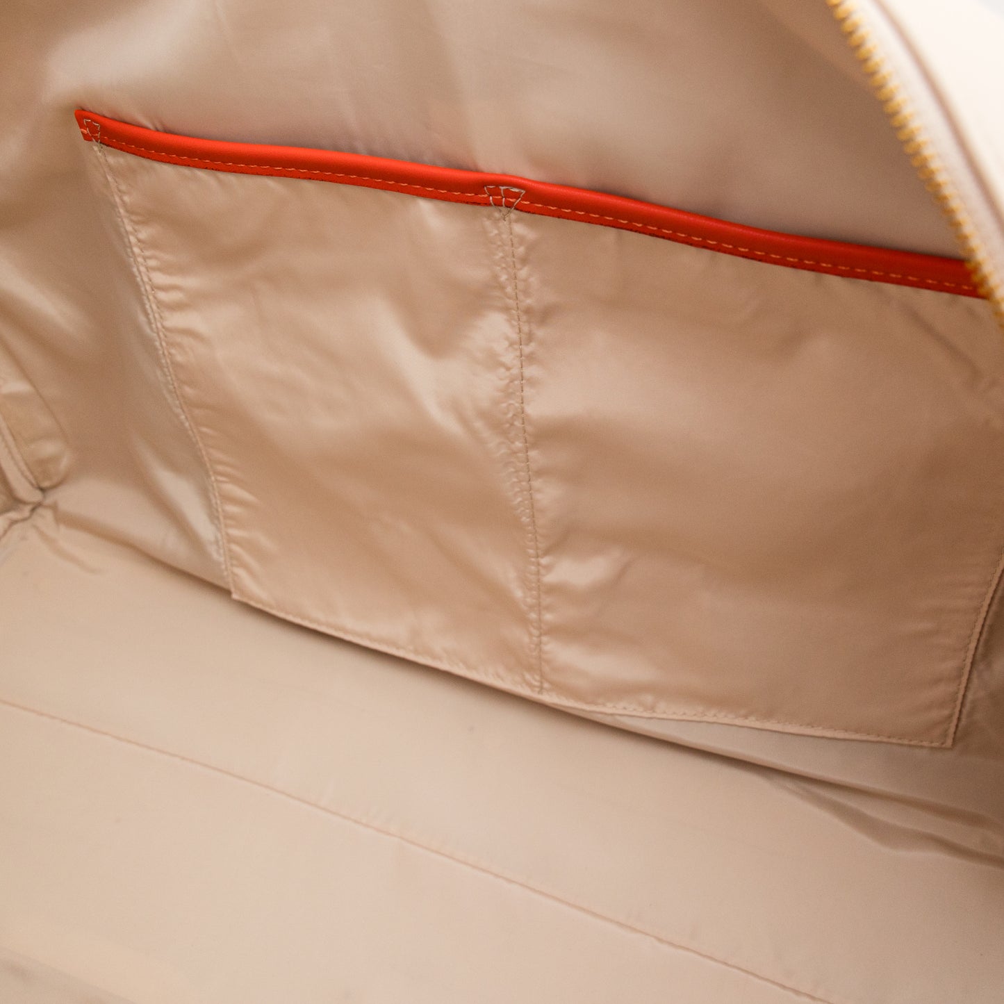 Close-up of beige duffel bag with orange stitching detail