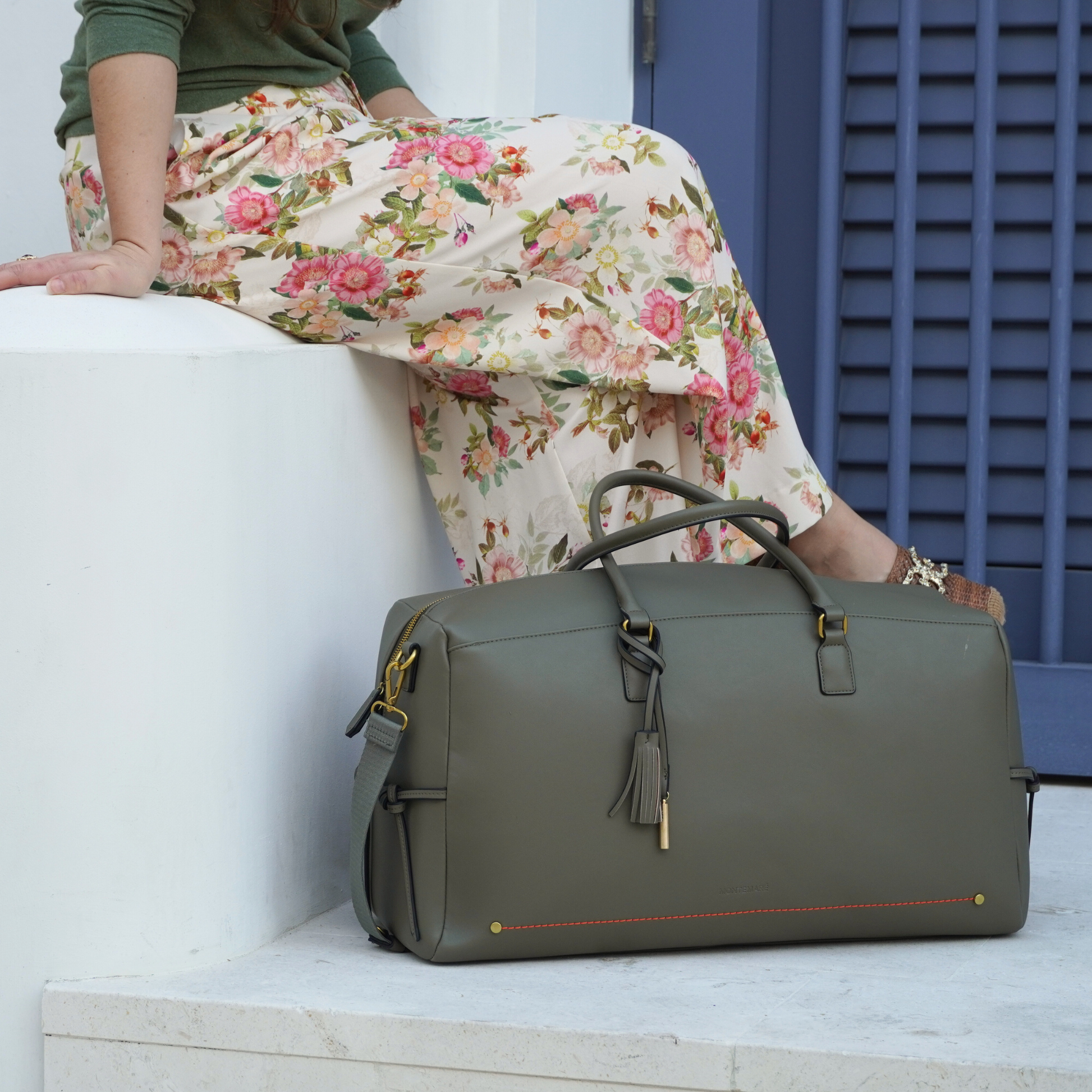 Woman wearing floral skirt with Montemare Duffel bag in olive colorway