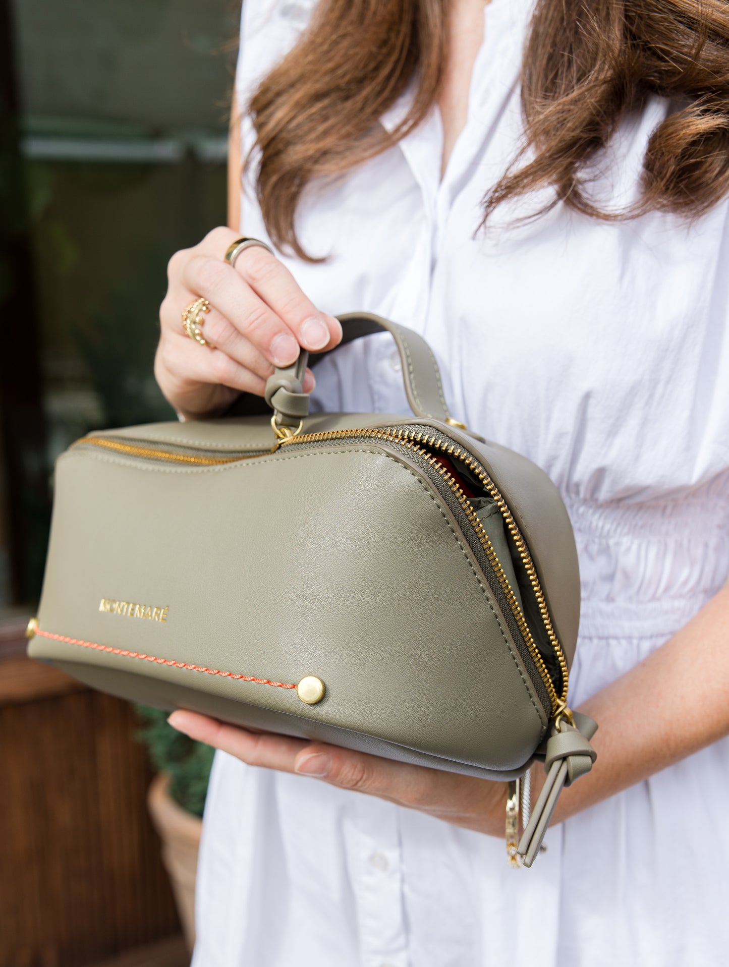 Person holding a green toiletry case with Montemare branding.