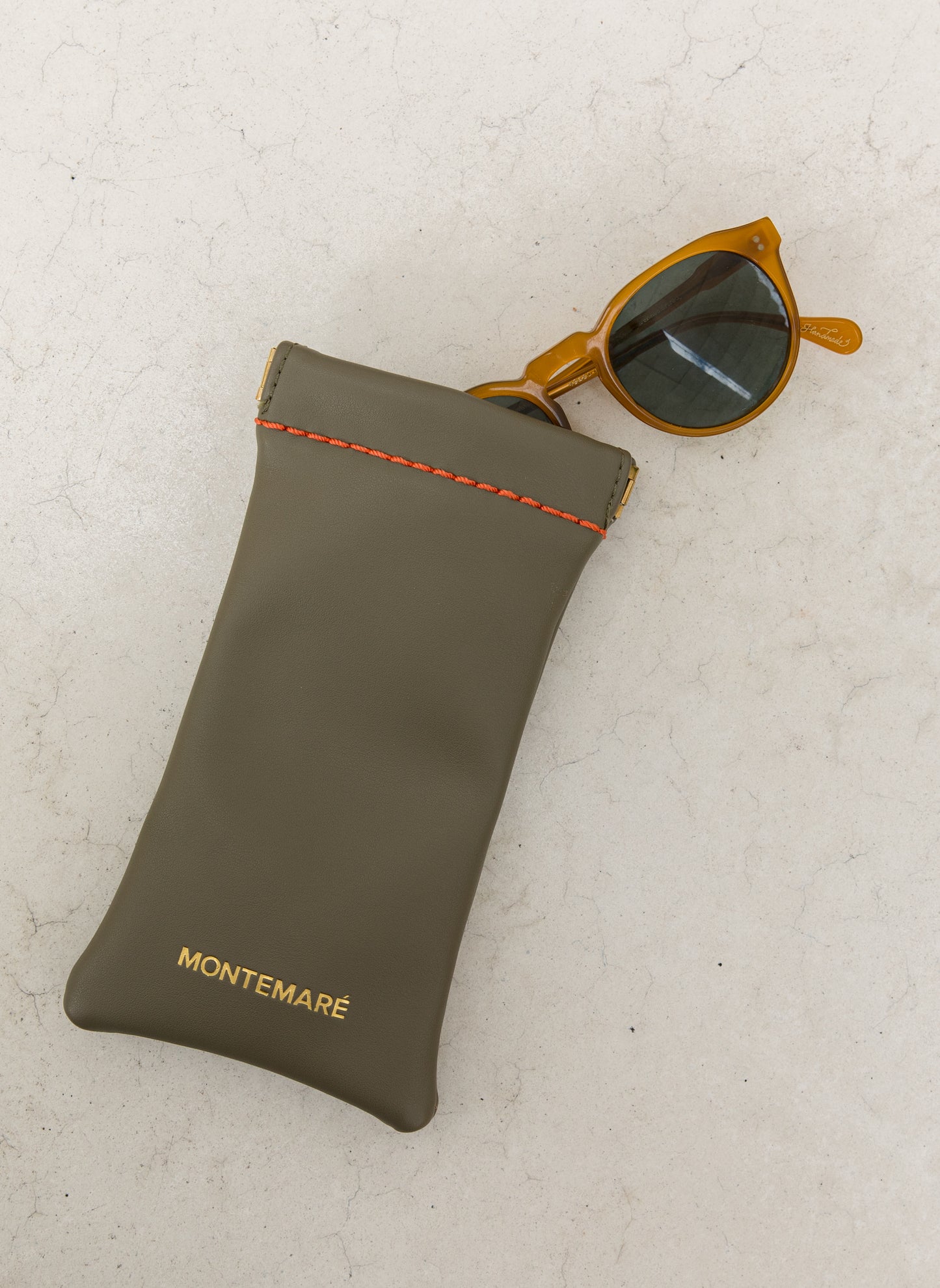 Green eyewear pouch with sunglasses on a light gray background