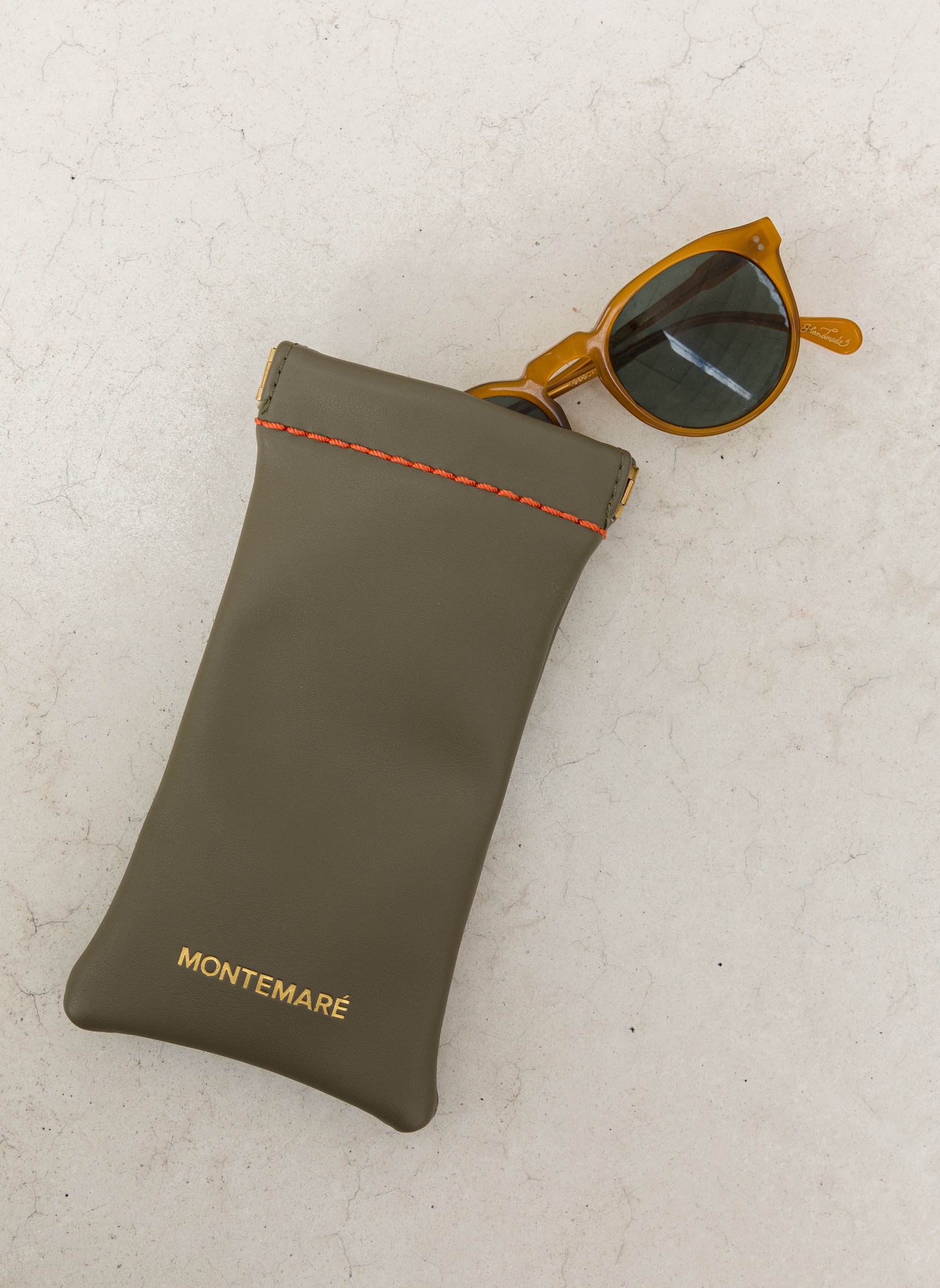 Green eyewear pouch with sunglasses on a light gray background