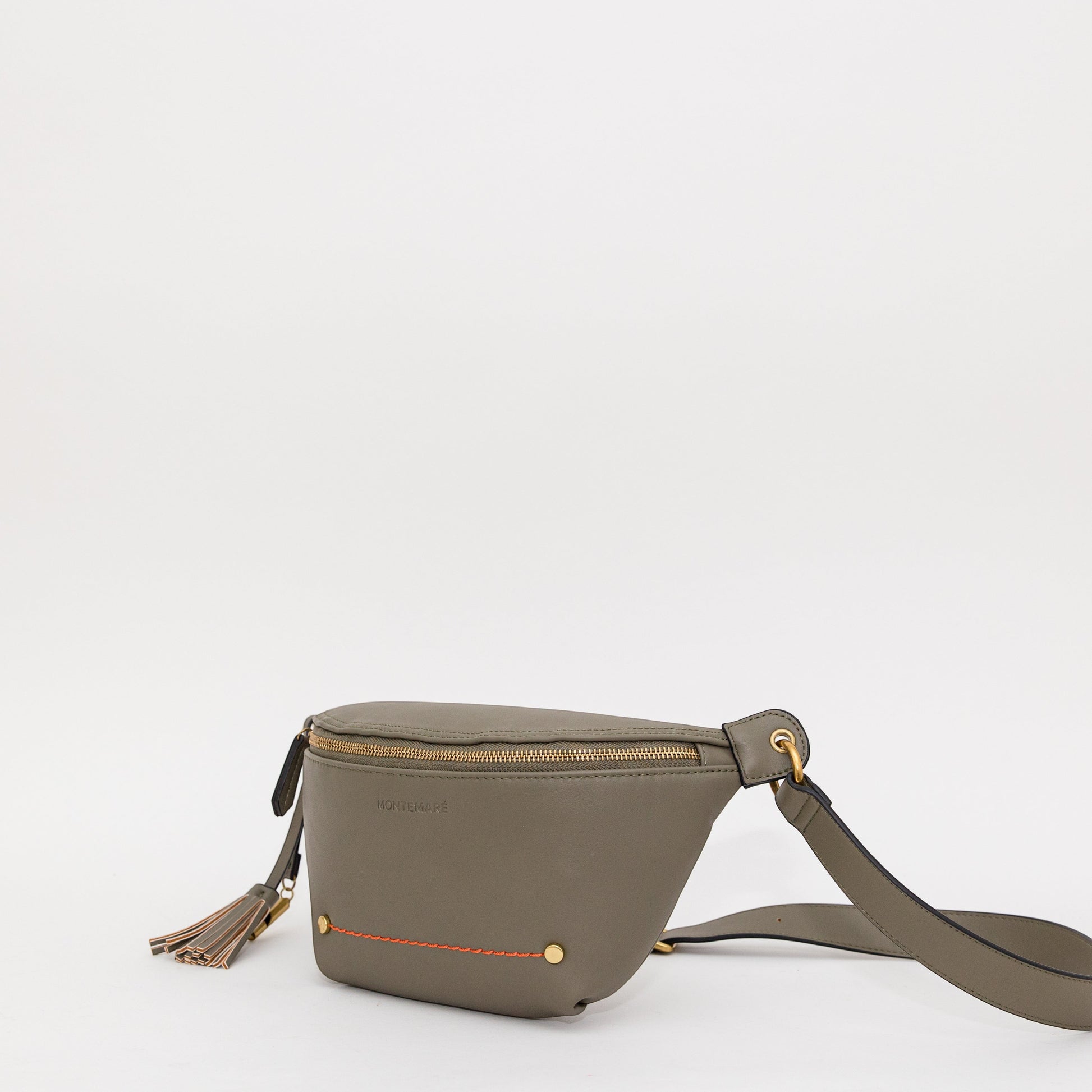 Green sling with bright orange stitching, brass-finished zipper and whistle tassel angled on a white background.