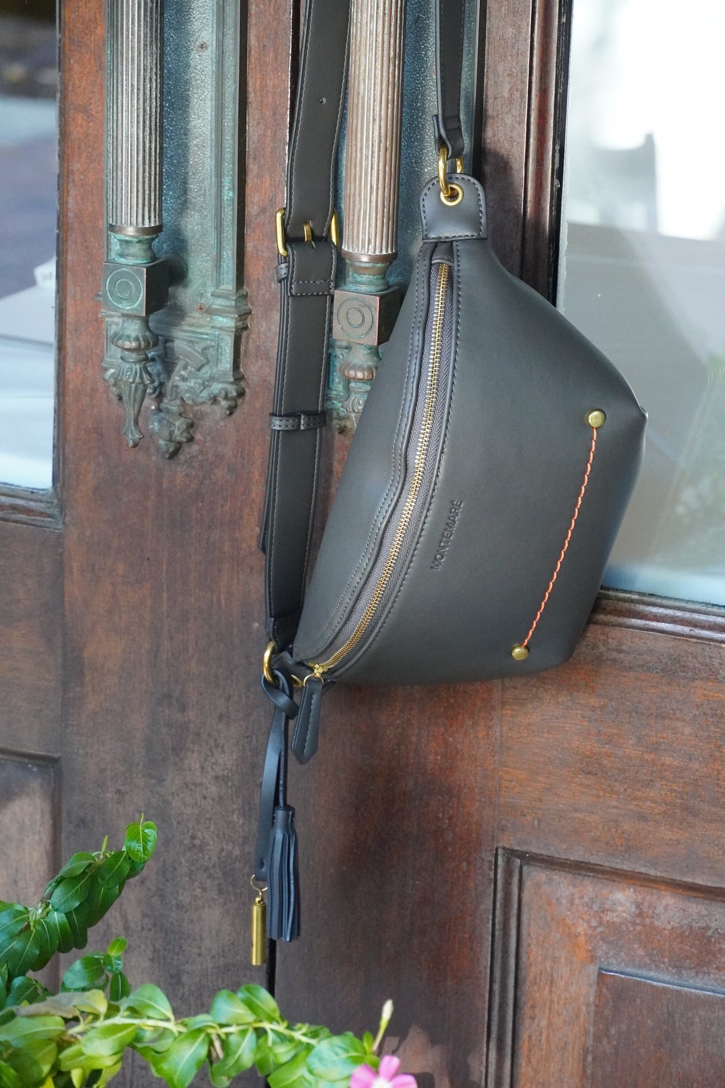 Black leather bag with gold zipper on a wooden surface