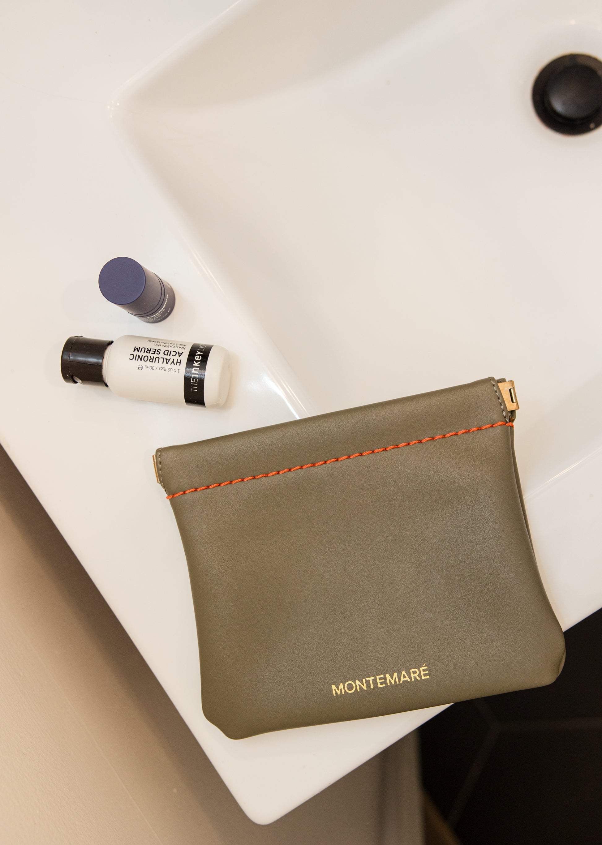 Green pouch with 'Montemare' branding on a white surface with skincare products.