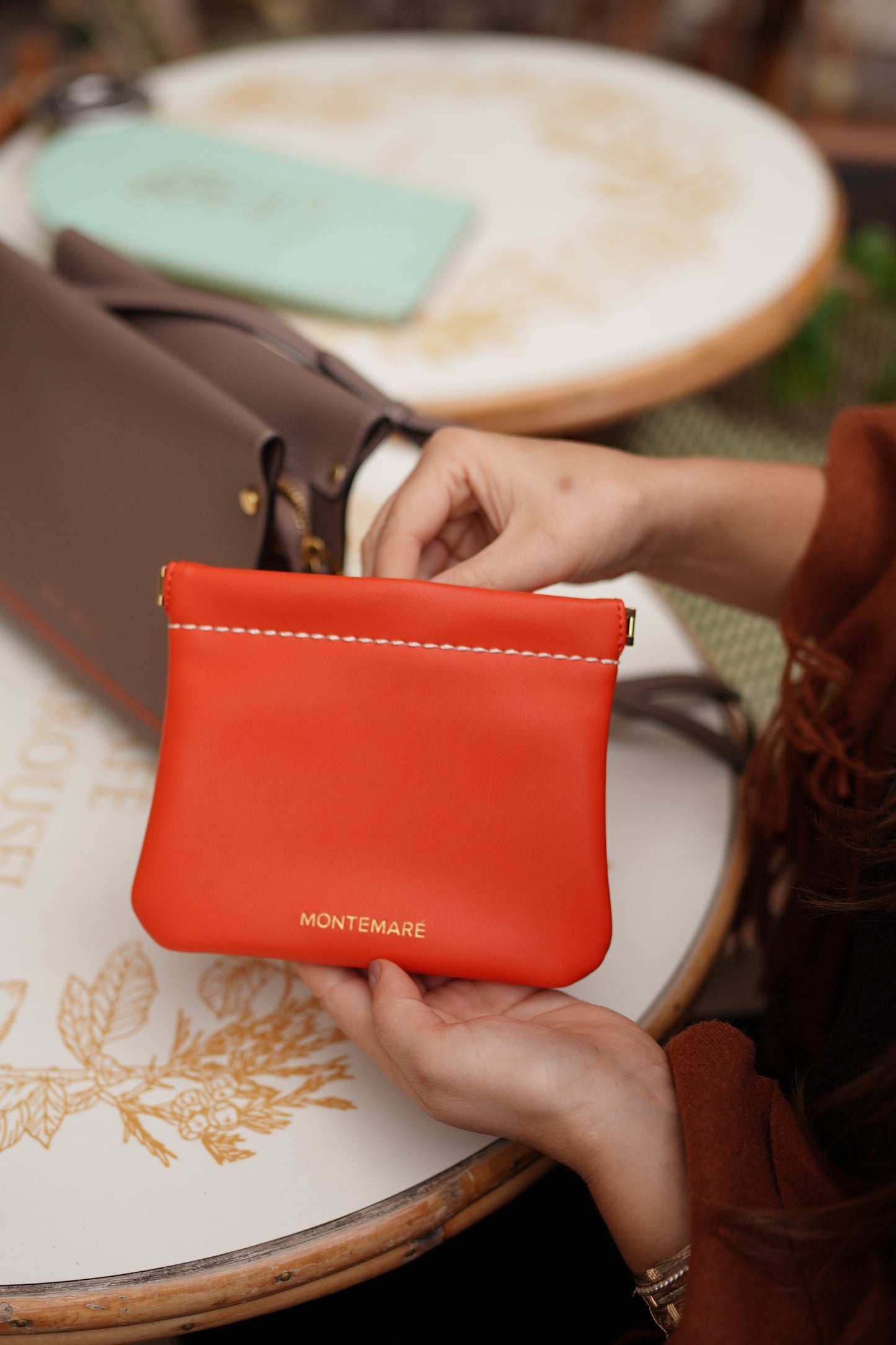 Person holding a red Montemare square pouch with a blurred background