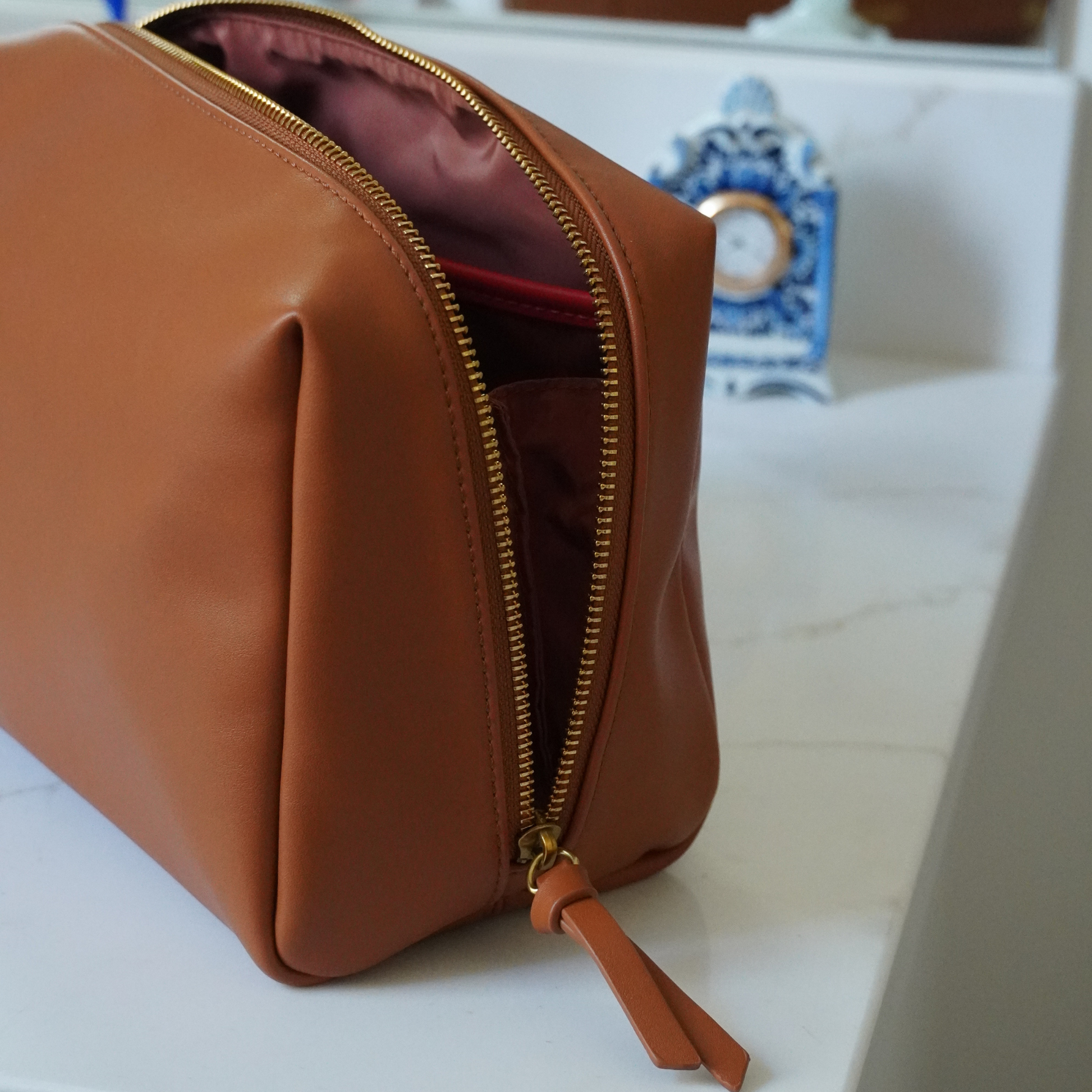 Close up of an opened Montemare brown standing toiletry case sitting on top of a marble surface