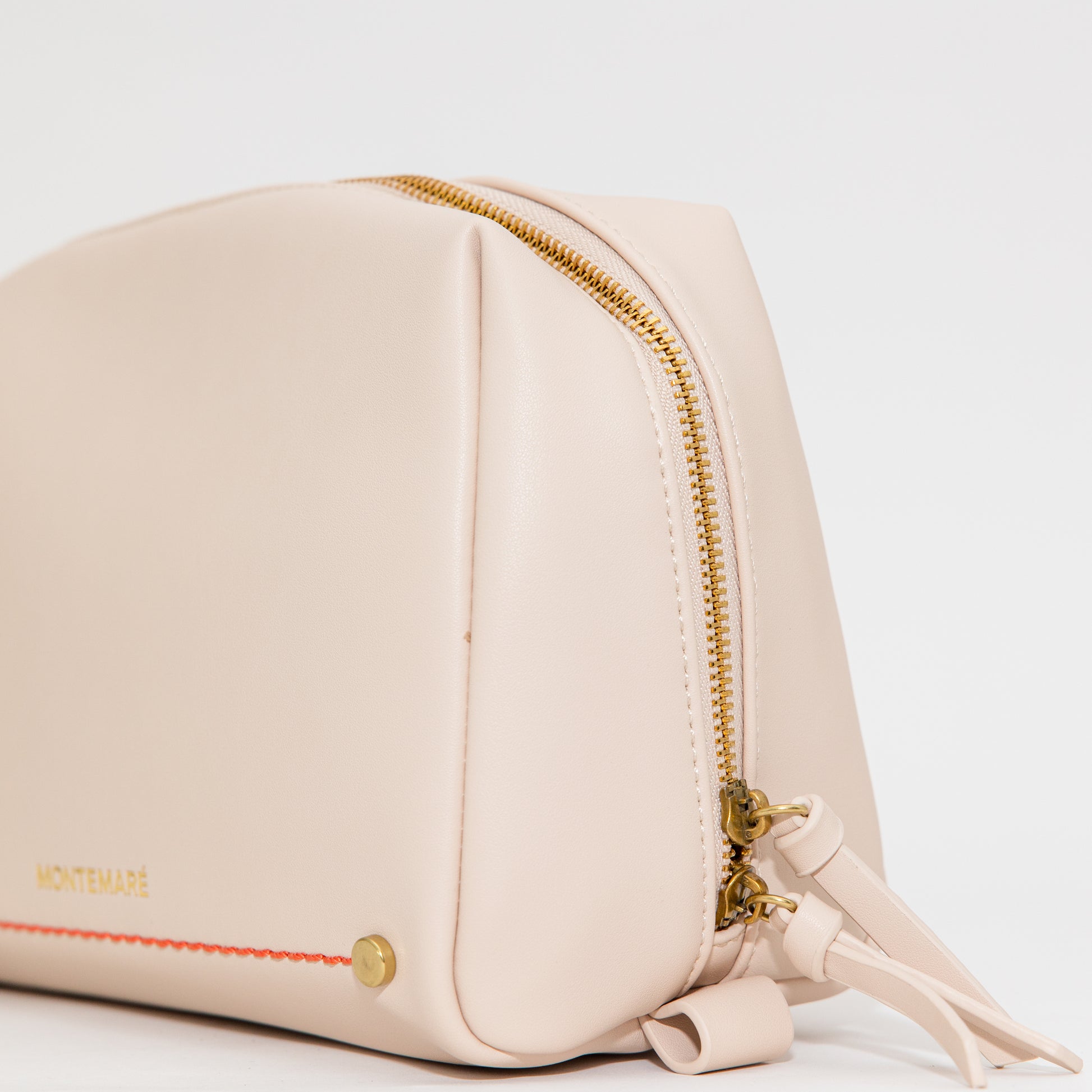 Ivory toiletry case with gold zipper on a light background