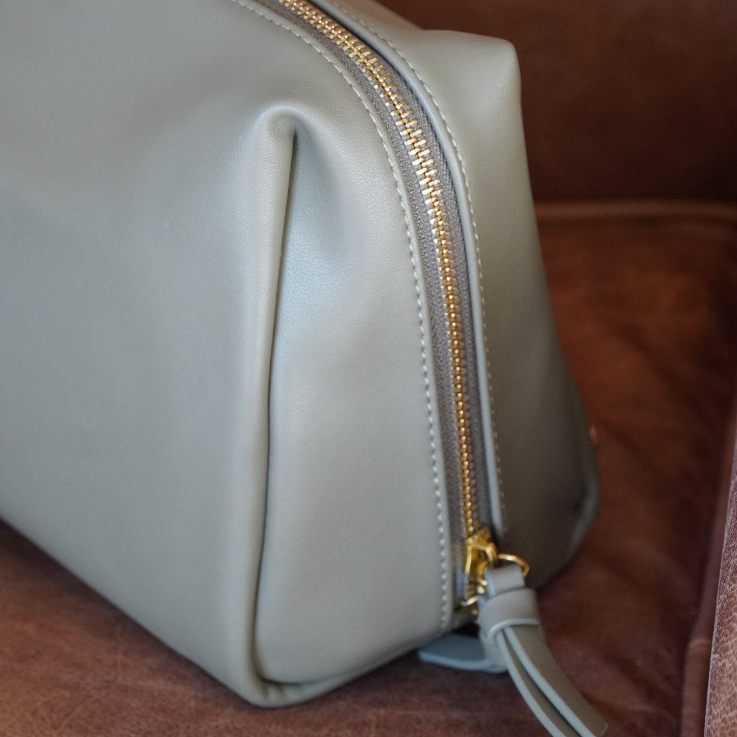 Light green toiletry case with a gold zipper on a brown surface