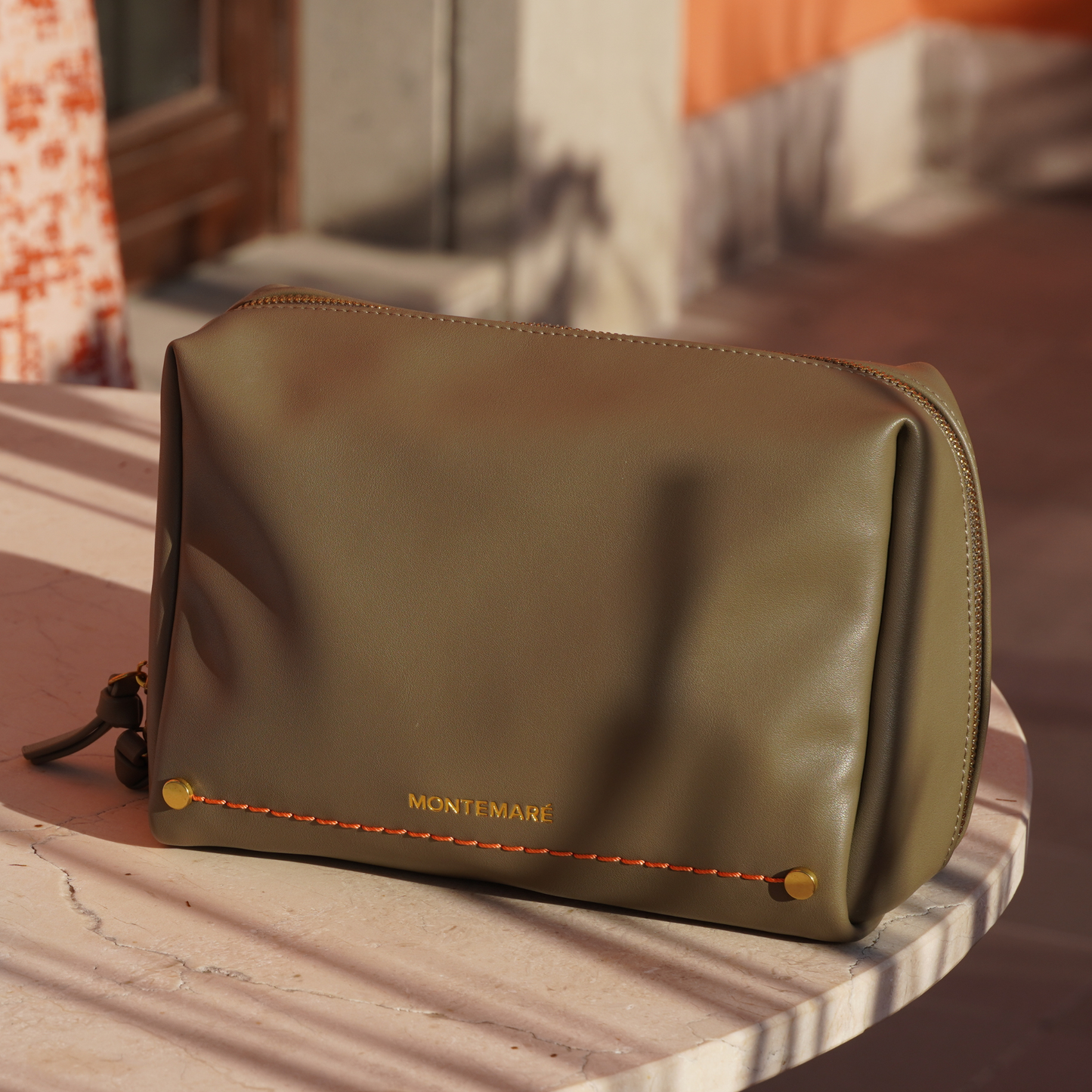 Green leather pouch with 'Montemare' branding on a marble surface.