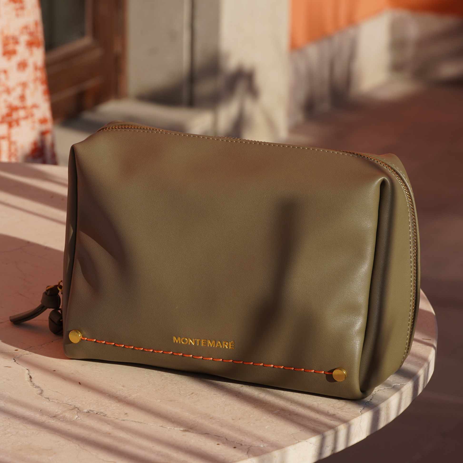Green leather pouch with 'Montemare' branding on a marble surface.