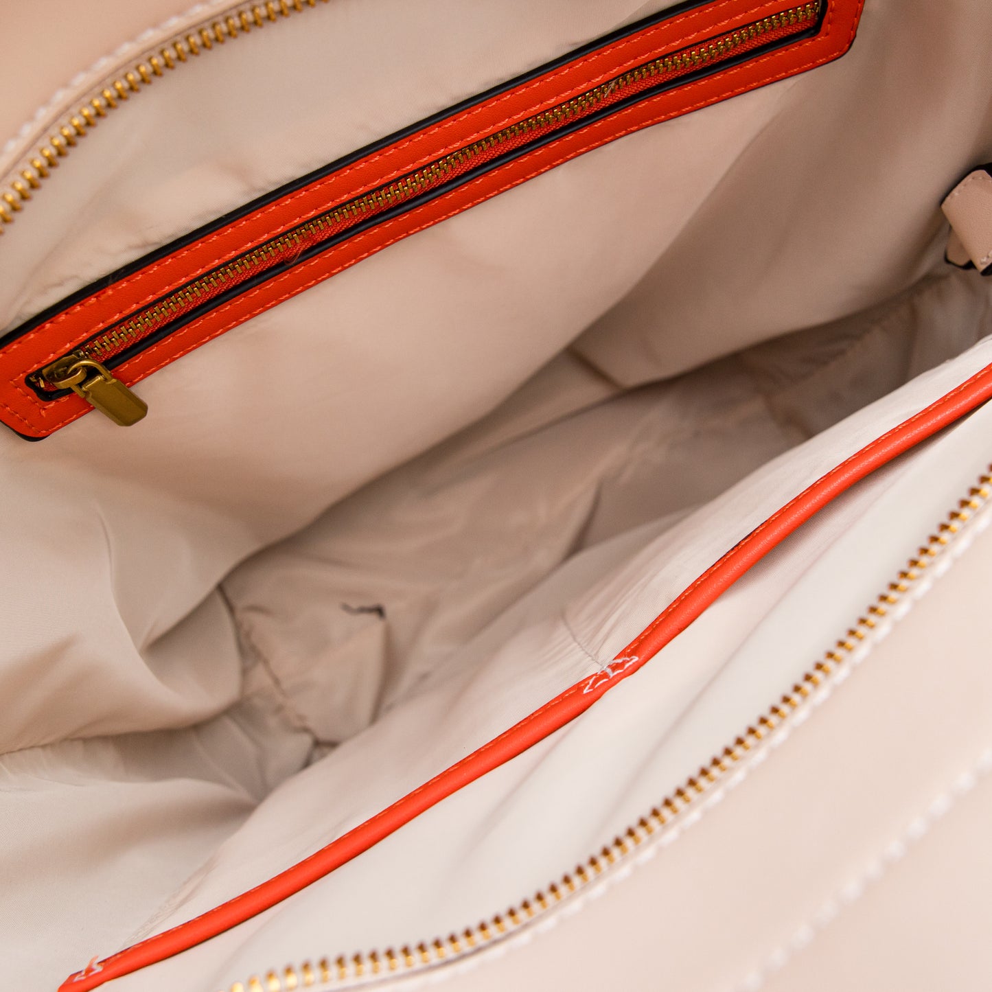 Close-up of a beige bag with a orange zipper