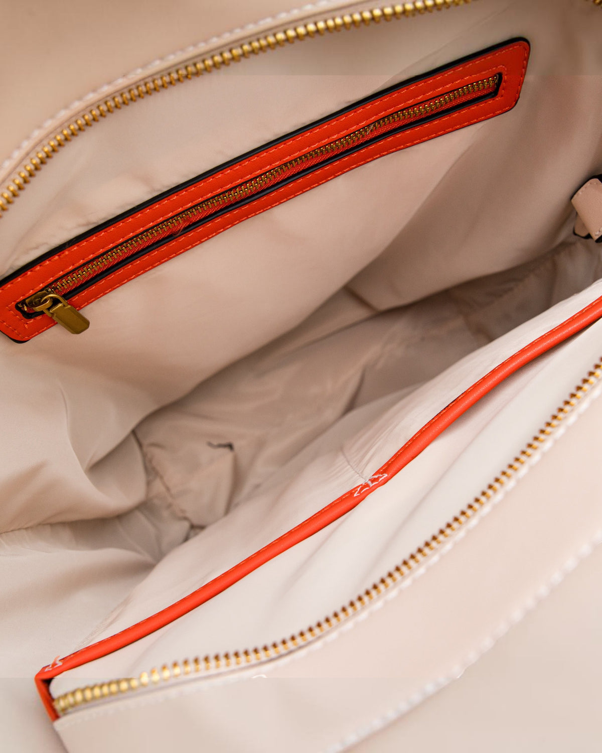 Close-up of a beige bag with a orange zipper
