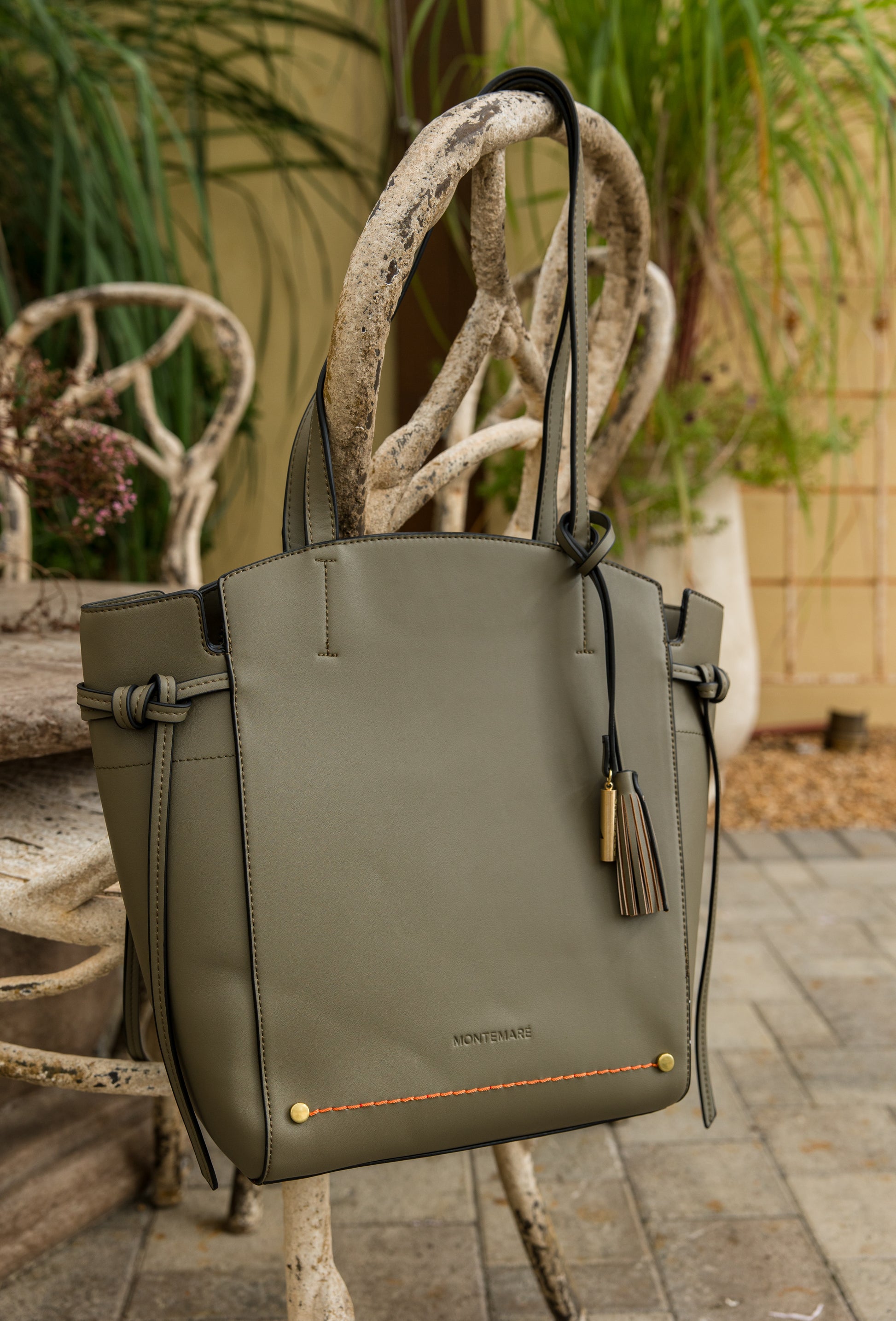 Green handbag with decorative handle against a garden background
