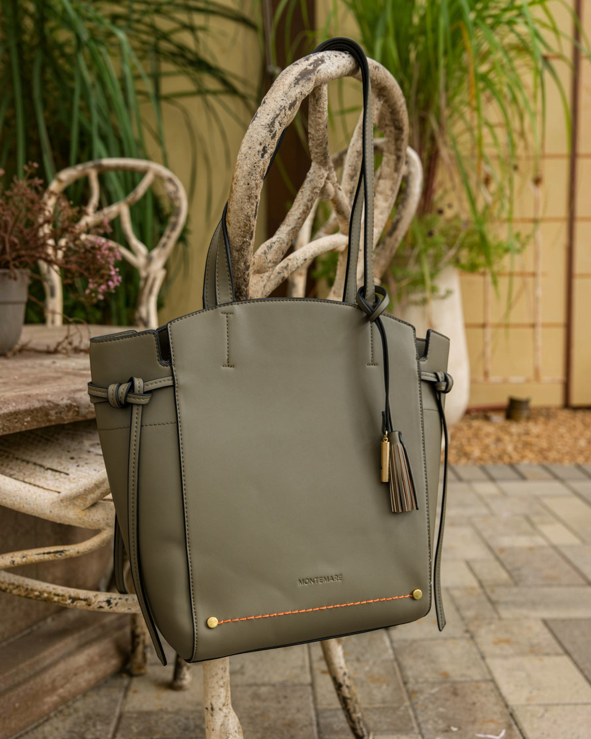 Green handbag with decorative handle against a garden background