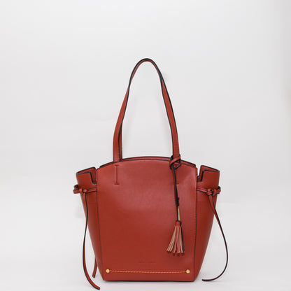 Terracotta leather handbag with a tassel on a white background