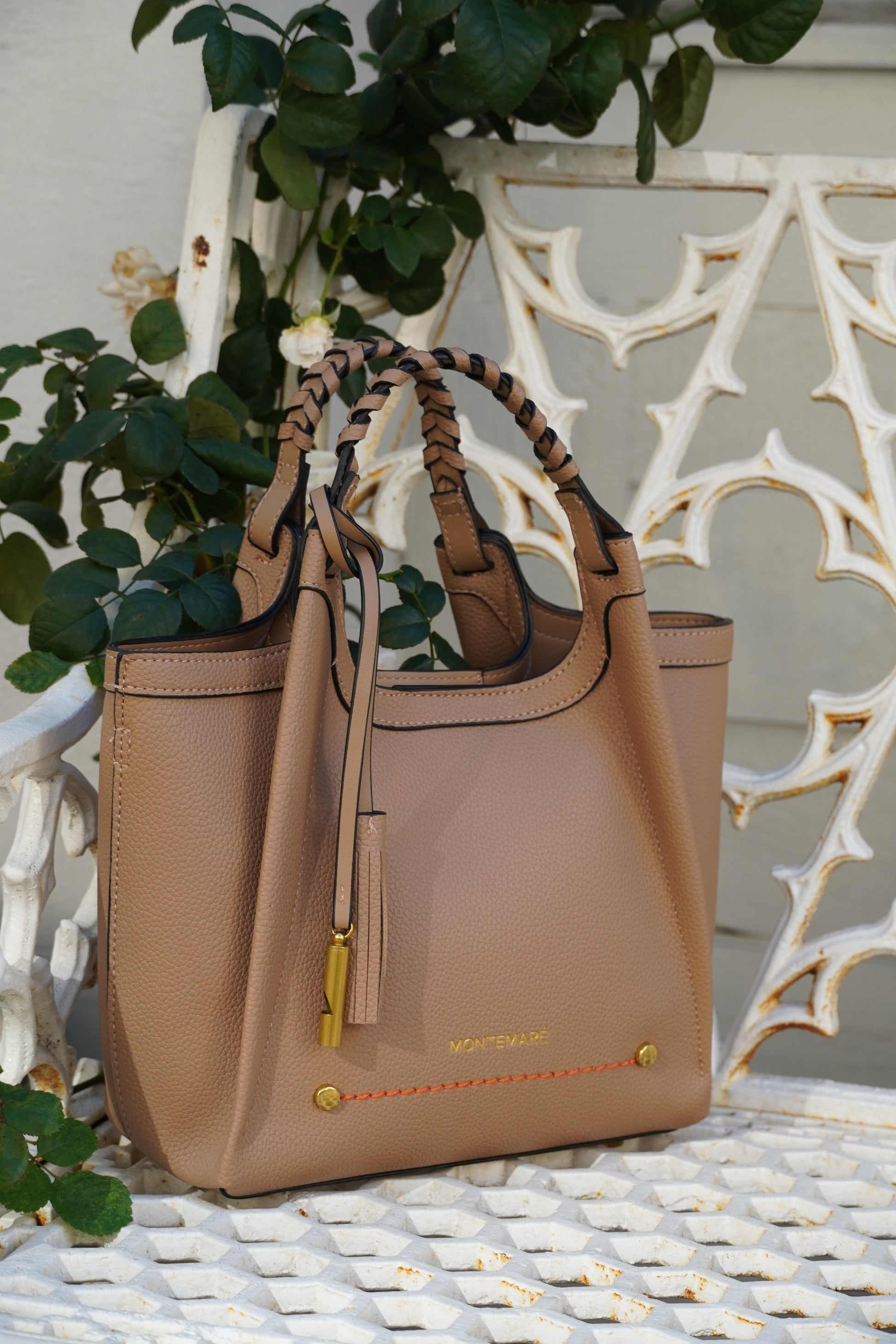 Latte crossbody bag with braided strap on a metal white bench