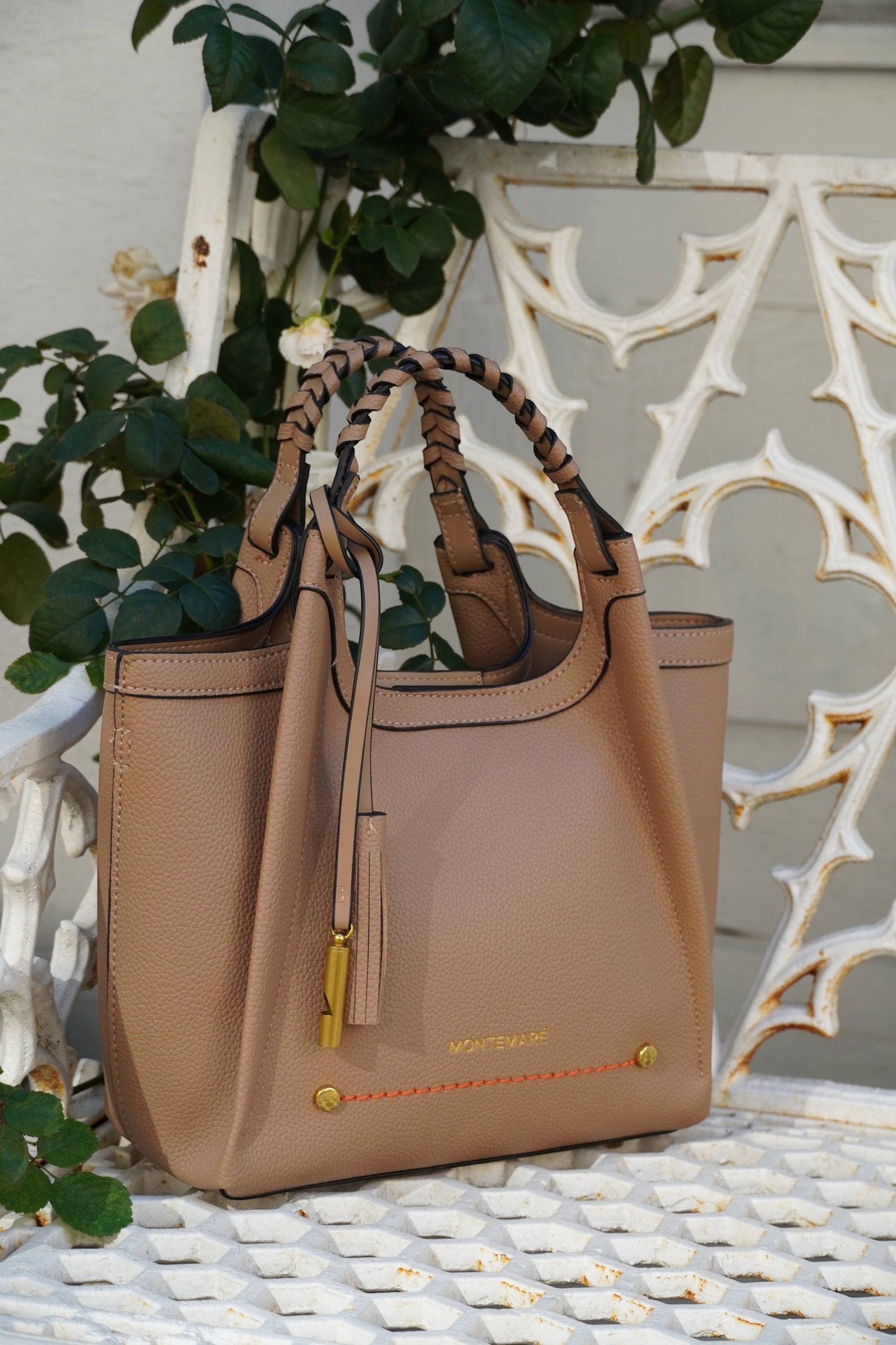 Latte crossbody bag with braided strap on a metal white bench