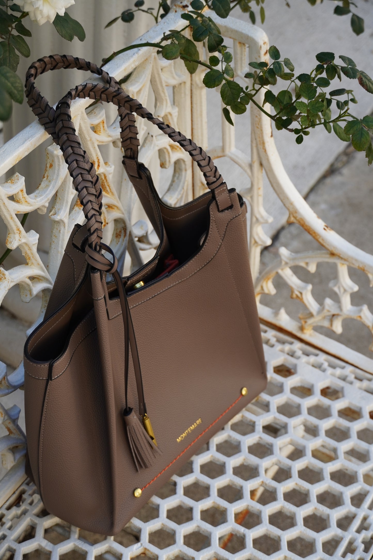 Brown leather handbag with braided handle on a decorative white background