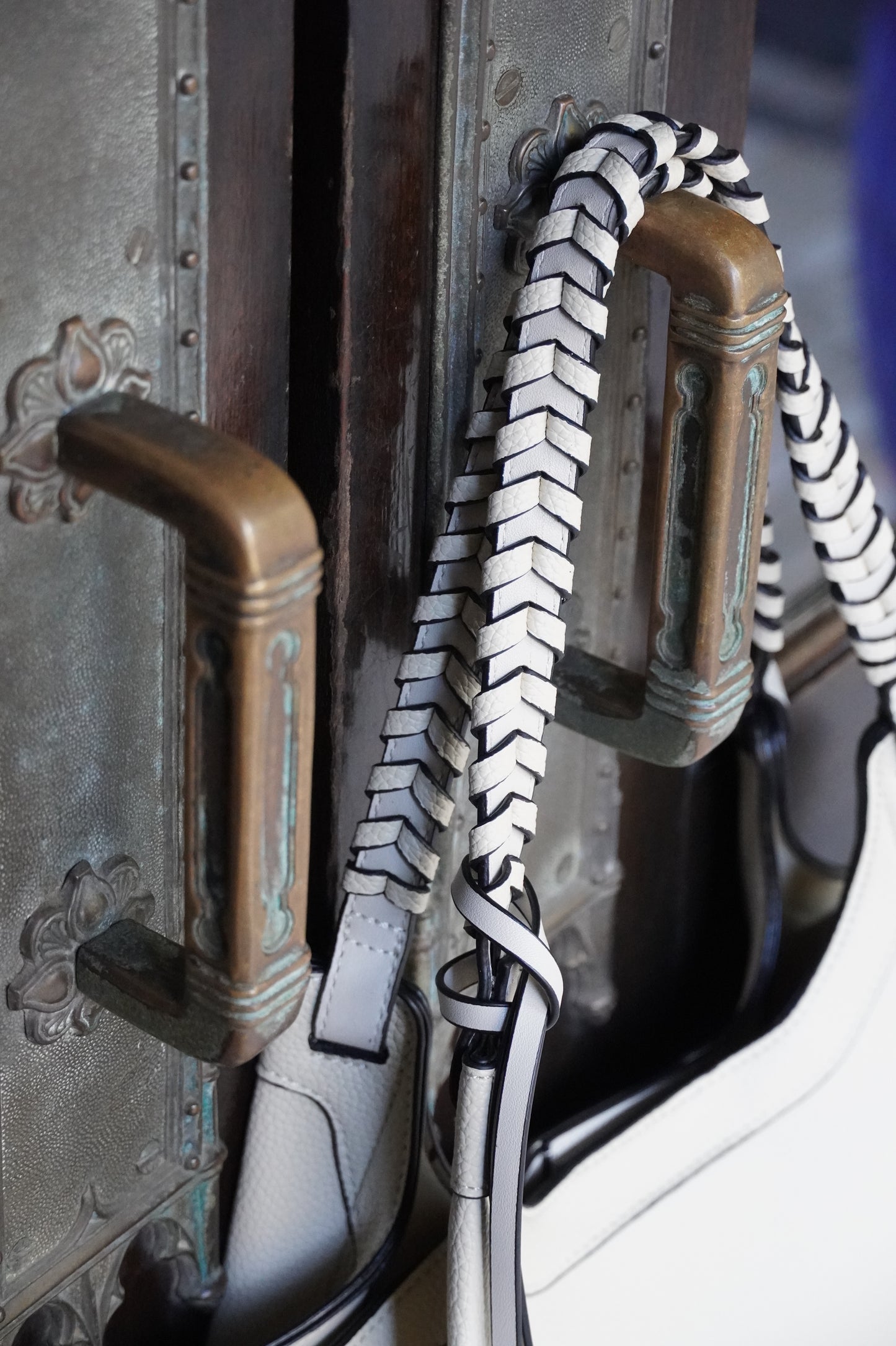 Close-up of a white handbag with decorative handles and zippers.