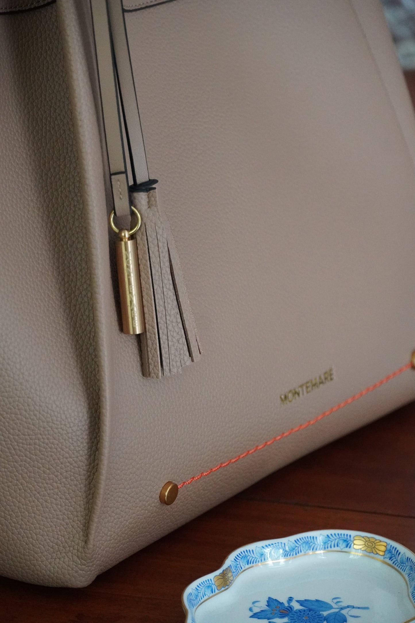 Beige handbag with a tassel detail on a wooden surface