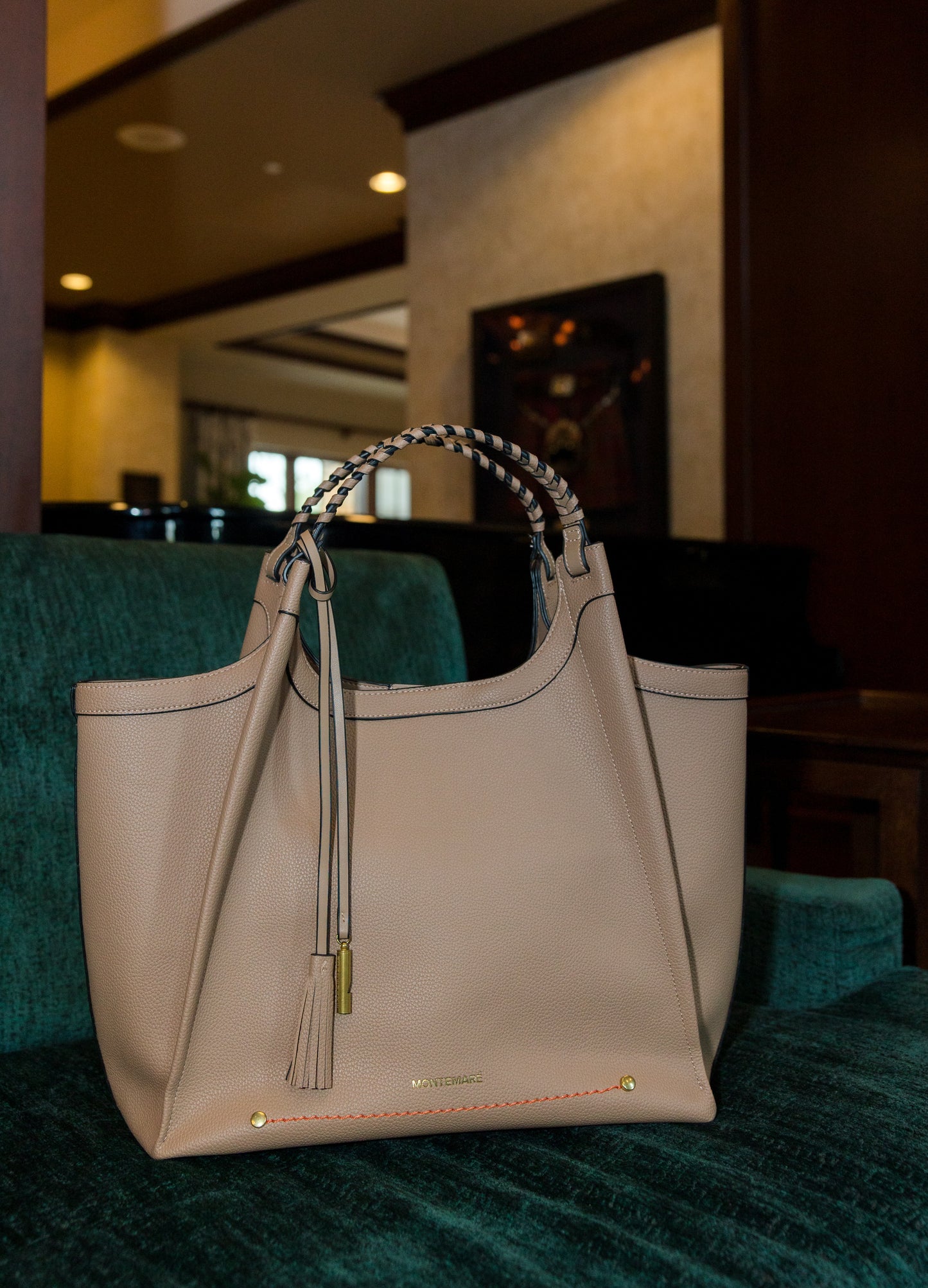 Beige handbag with tassels on a green couch