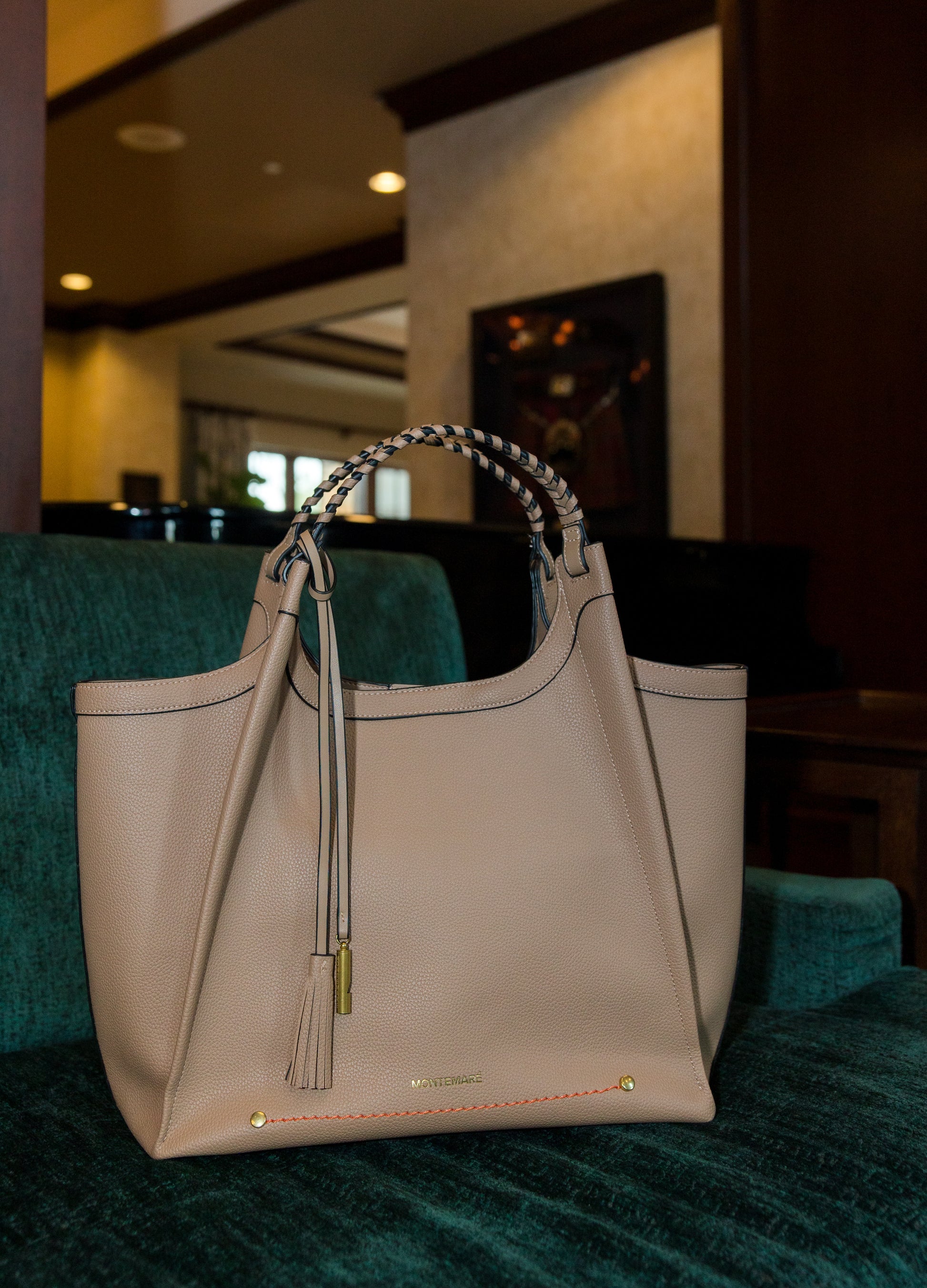 Beige handbag with tassels on a green couch