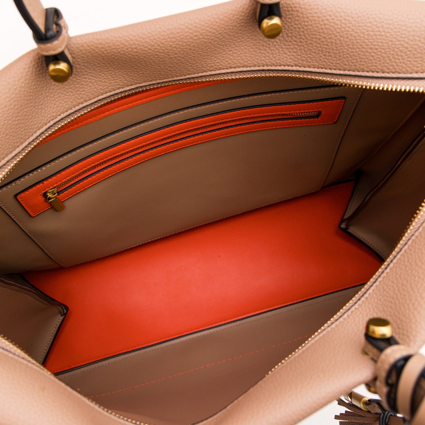 Close-up of a beige leather handbag with orange interior