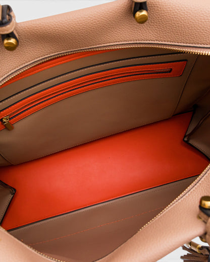 Close-up of a beige leather handbag with orange interior