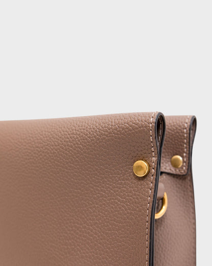 Close-up of a brown leather handbag with gold hardware on a white background