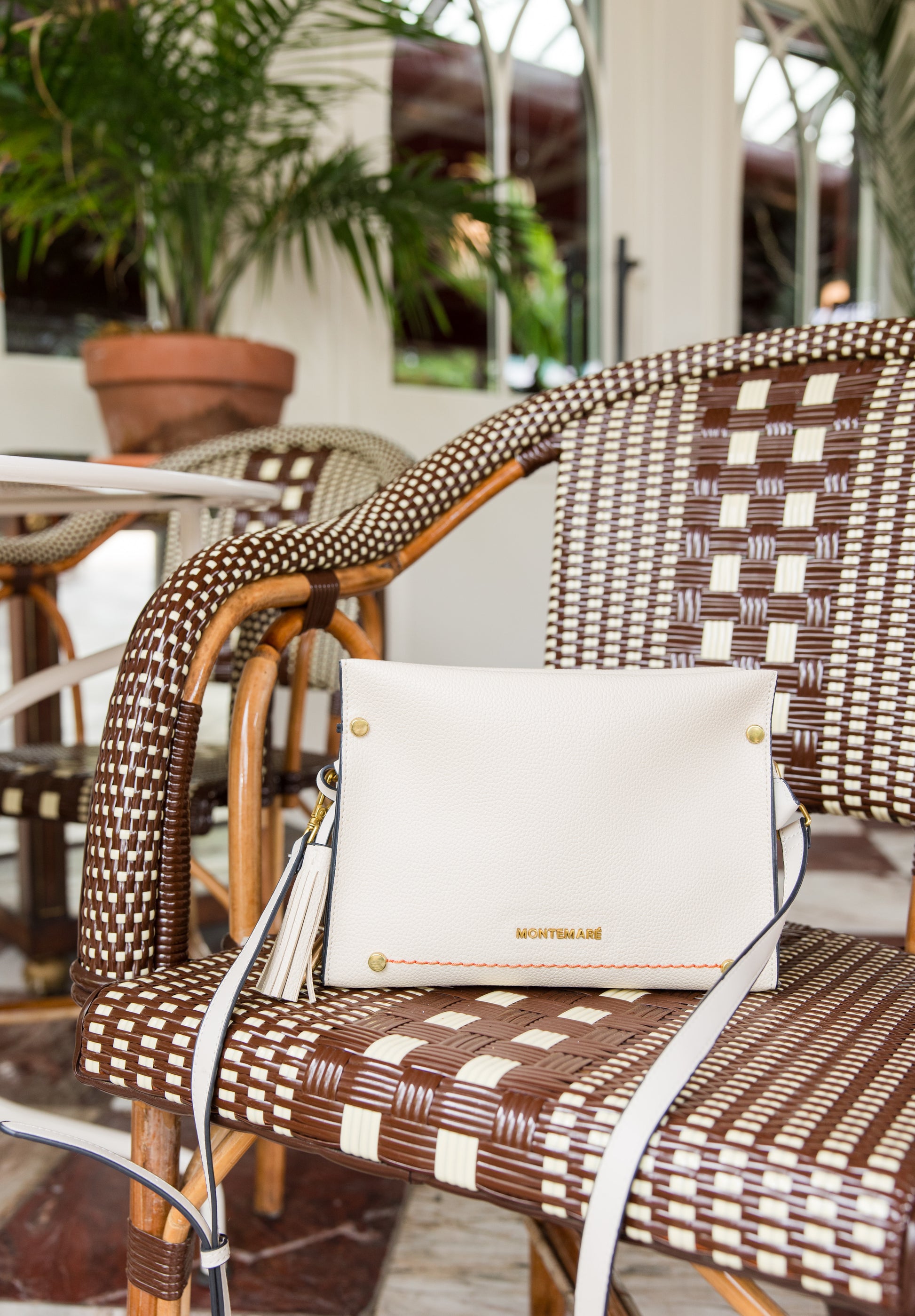 White handbag on a wicker chair with blurred outdoor background