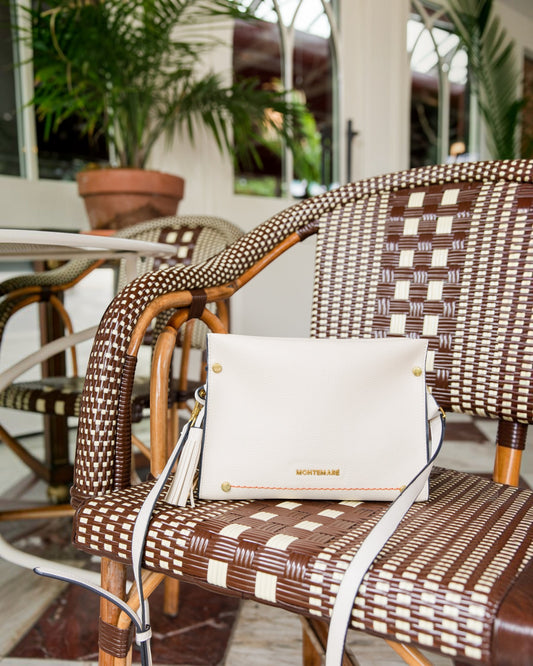 White handbag on a wicker chair with blurred outdoor background