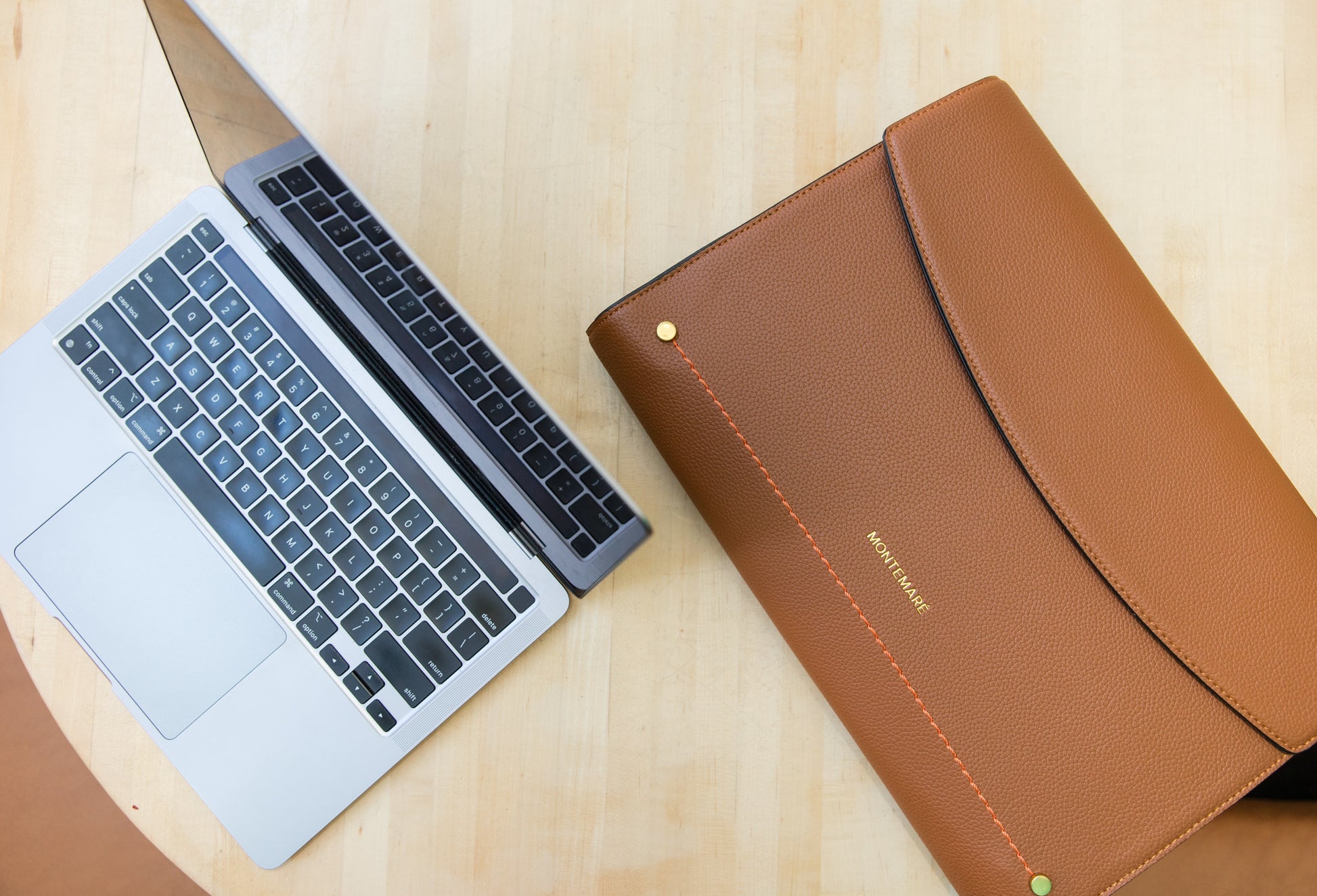 Laptop and brown leather case on a wooden surface