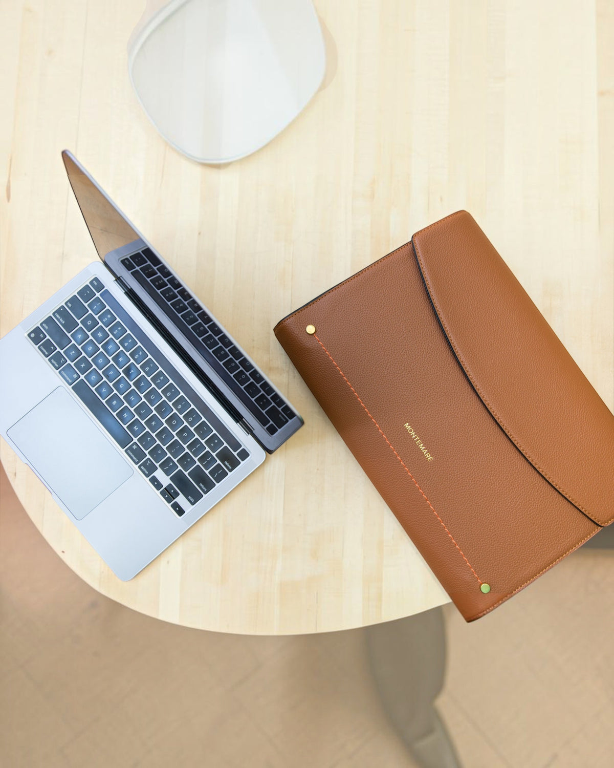 Laptop and brown leather case on a wooden surface