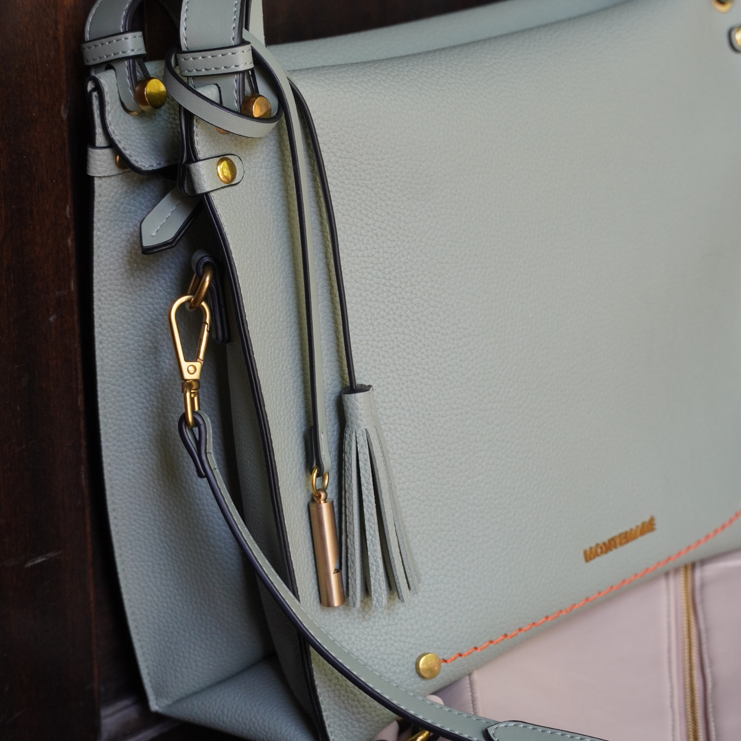 Close up shot of Montemare Vienna Shoulder Bag in Blake's blue colorway with adjustable strap, tassel on wooden wall background