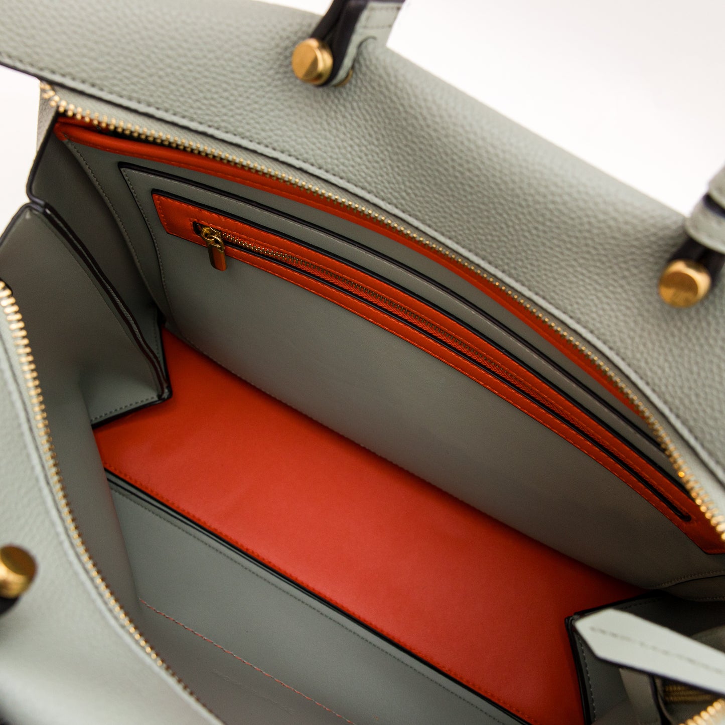 Blue handbag with gold zippers and orange interior
